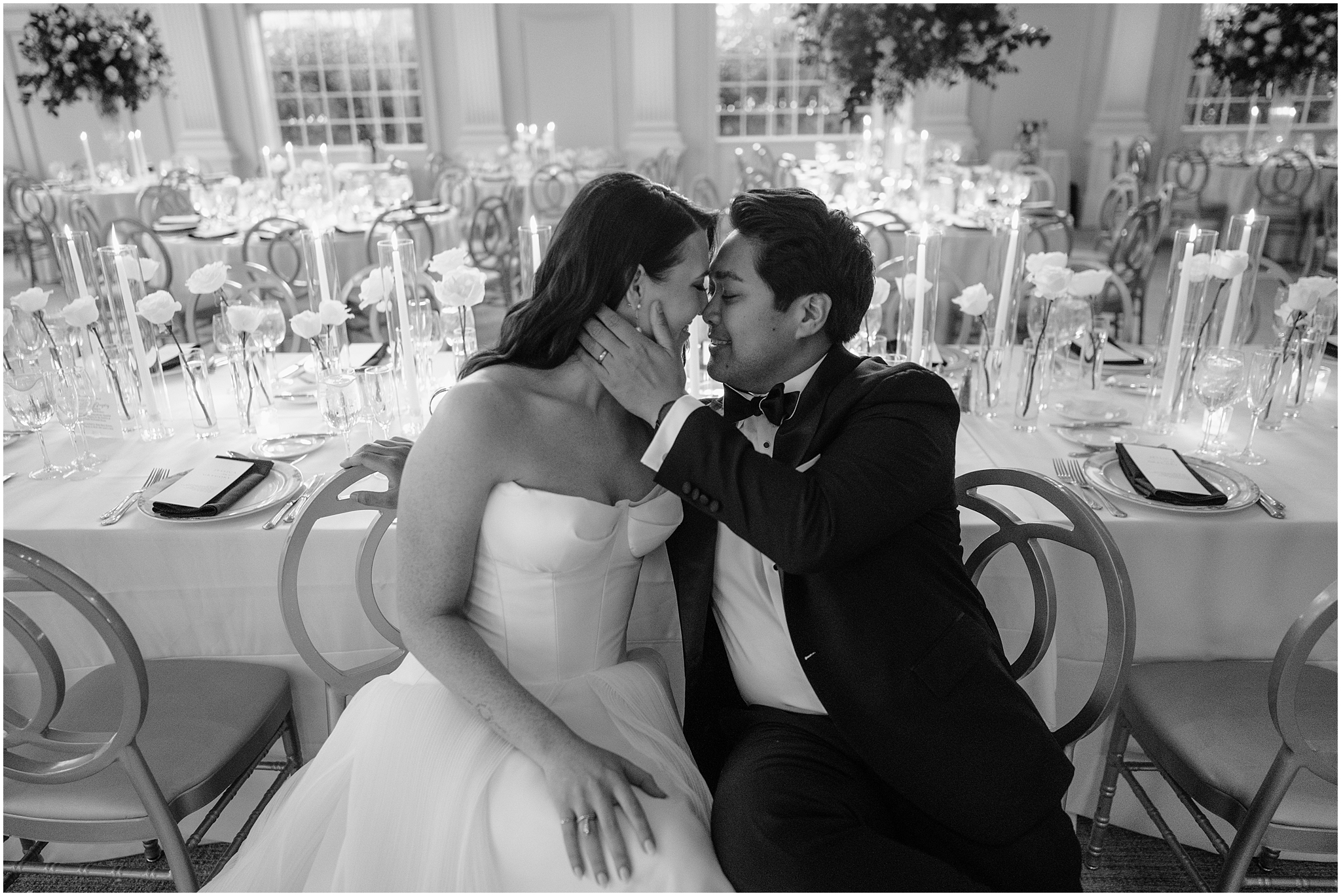 bride and groom lean together sitting in chairs by tables for reception 