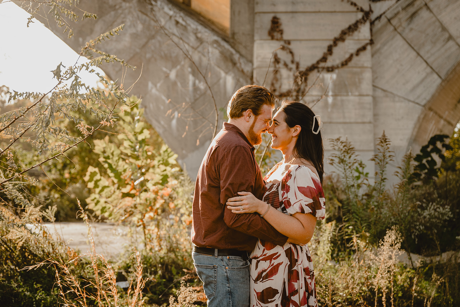engaged couple hugs by stone bridge near Schuylkill River