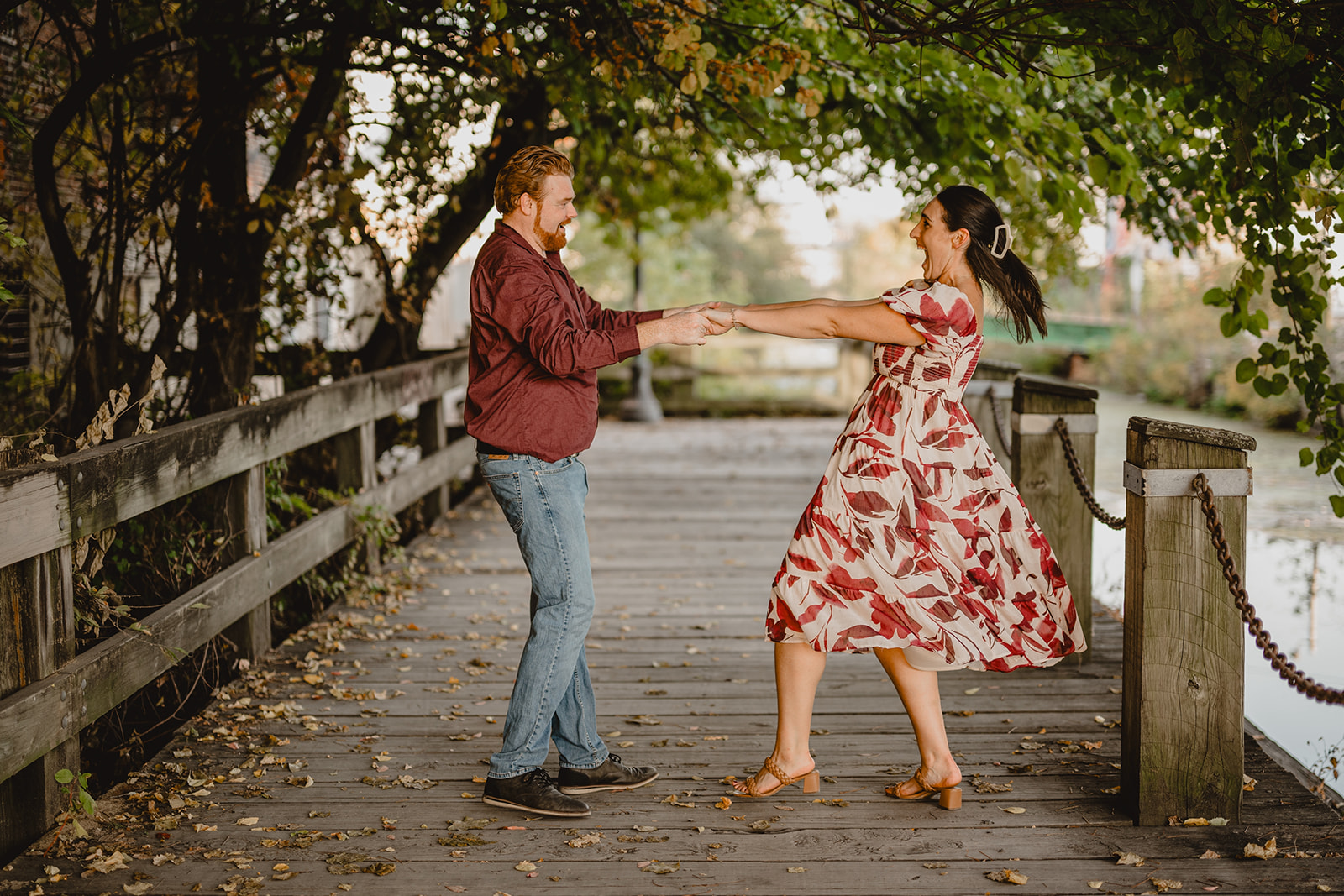 couple twirls on wooden bridge during Manayunk engagement session in Philly PA