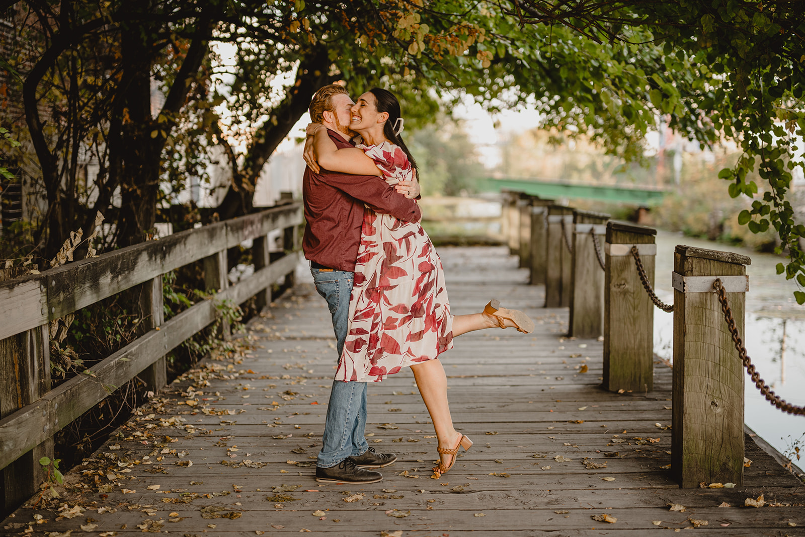 man lifts up woman kissing her on wooden bridge during Manayunk engagement session in Philly PA