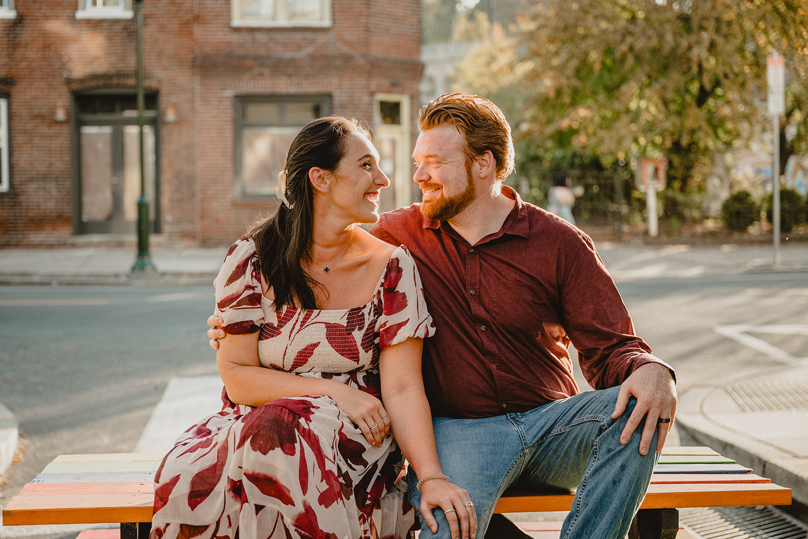 couple sits on table laughing during Manayunk engagement session in Philly PA