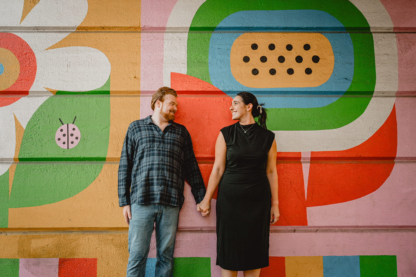 man and woman hold hands smiling during engagement session in Manayunk in Philly PA