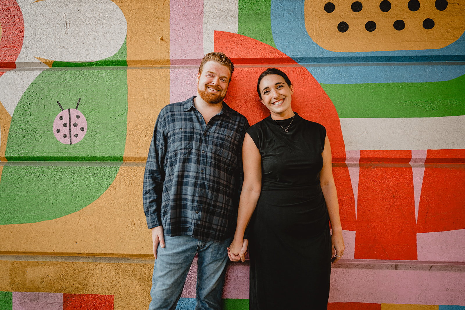 man and woman hold hands by colorful mural in Manayunk in Philly PA