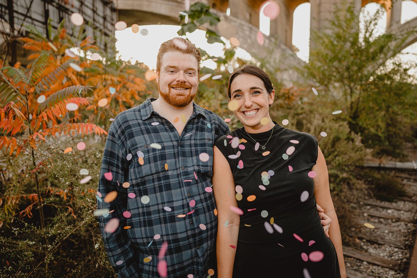 engaged couple throws confetti standing in Manayunk neighborhood
