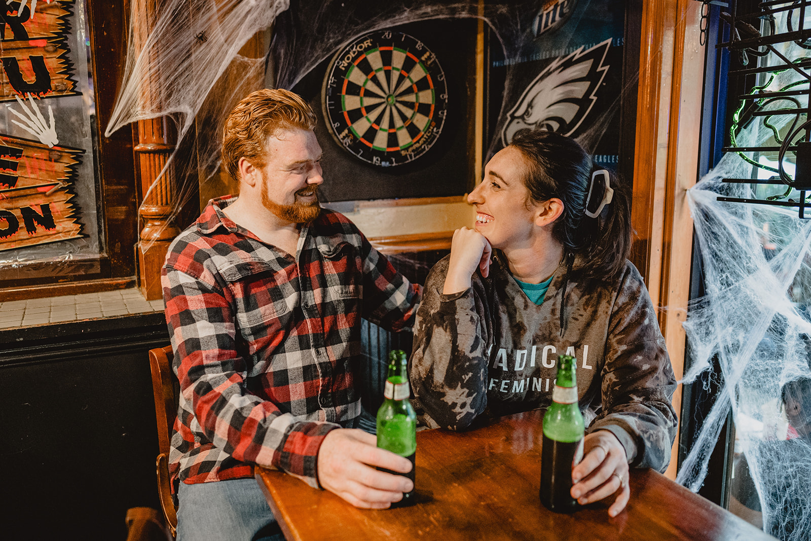 engaged couple smiles at each other in Manayunk bar