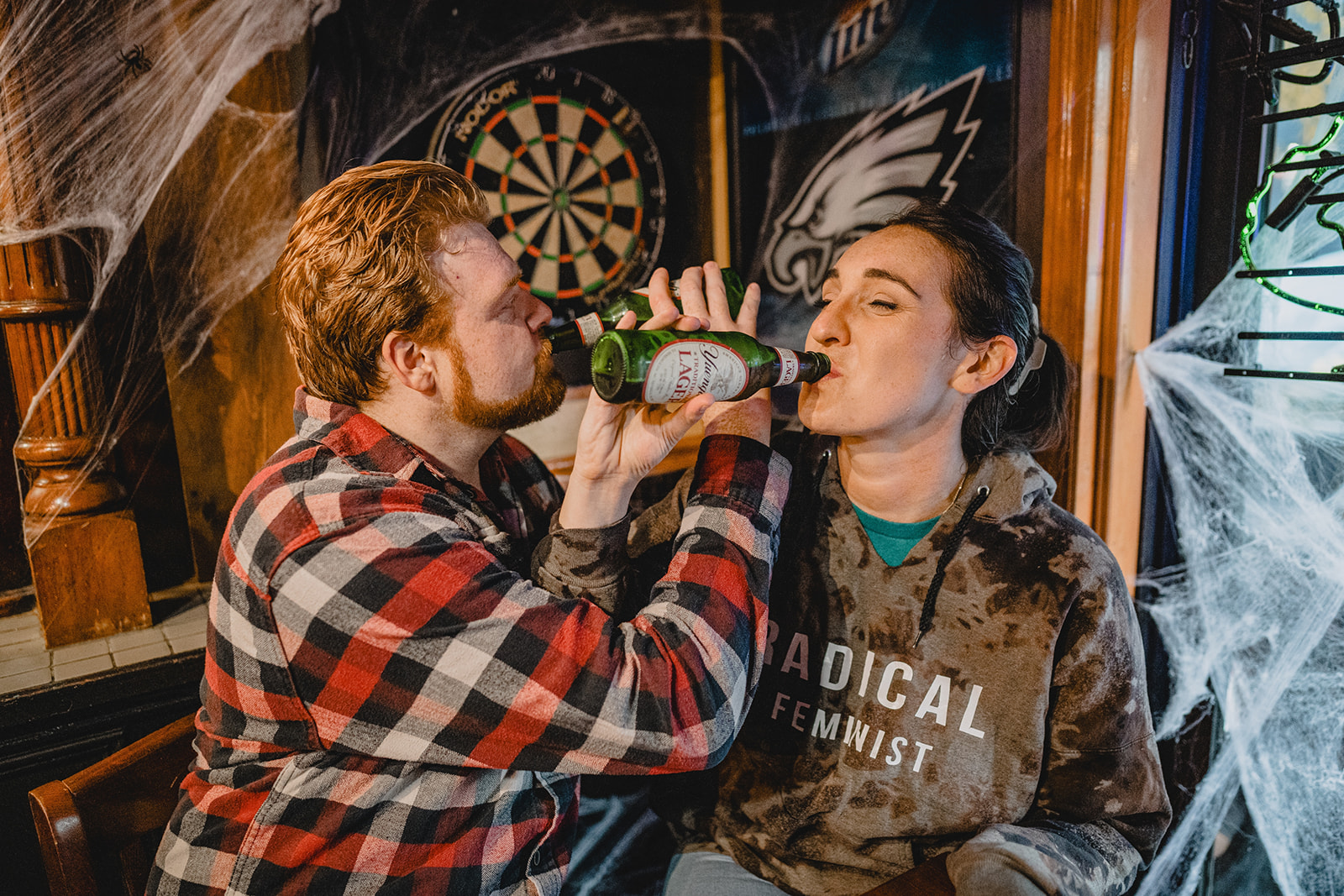 couple links arms and drinks beer in bar in Philly PA