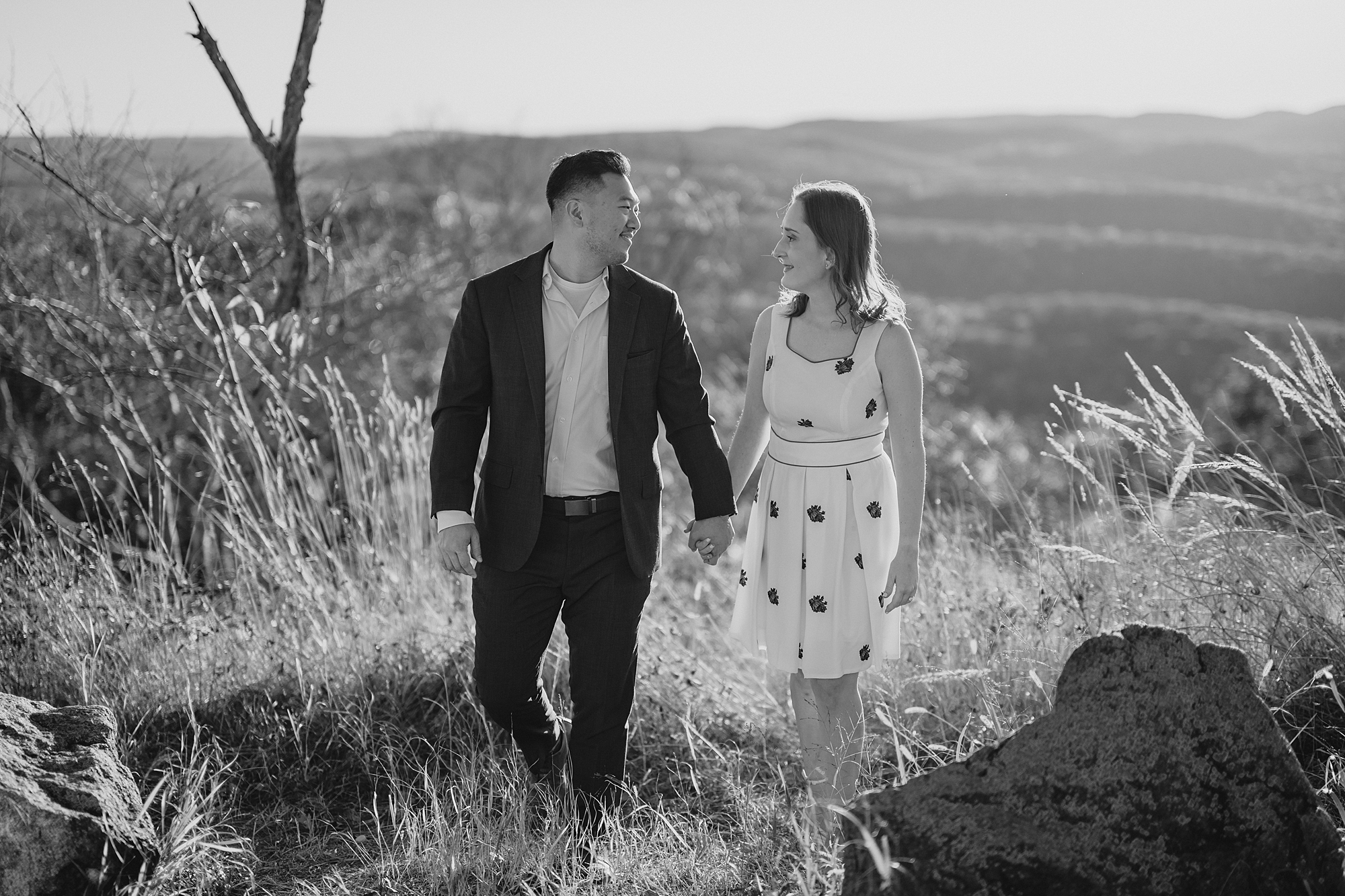 engaged couple holds hands walking on top of Bear Mountain in the Hudson Valley