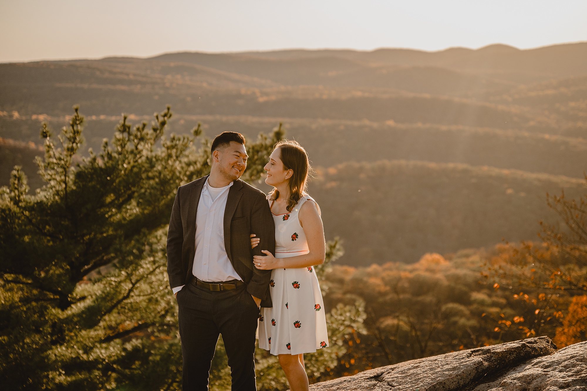 woman looks at man holding onto his arm at sunset 