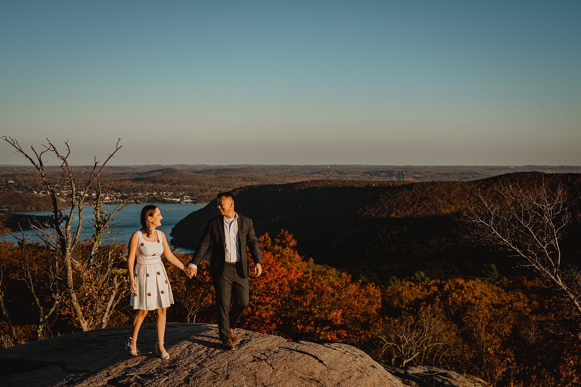 couple holds hands at sunset during fall engagement session on Bear Mountain