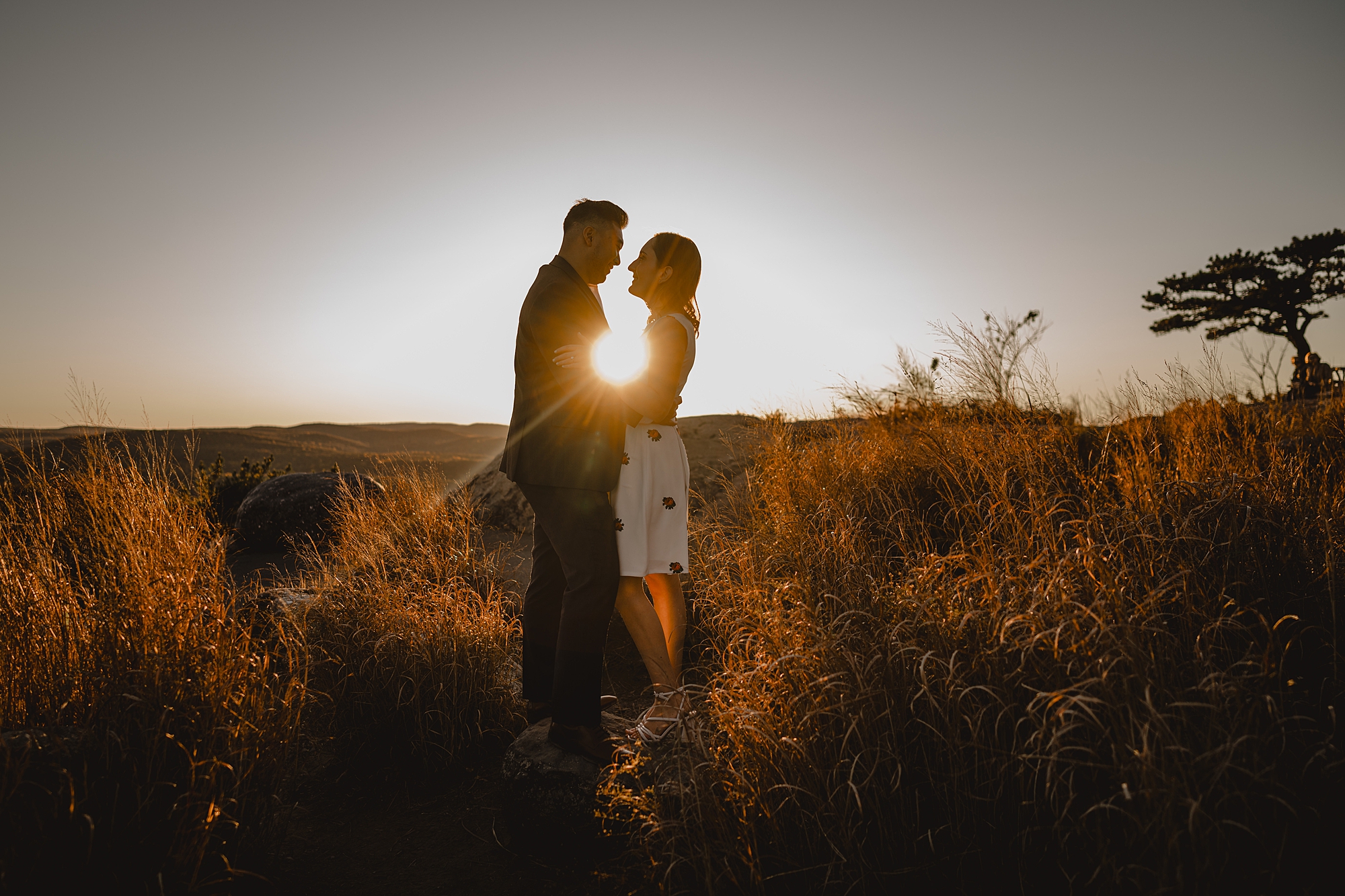 man and woman hug in front of sunset during fall engagement session on Bear Mountain