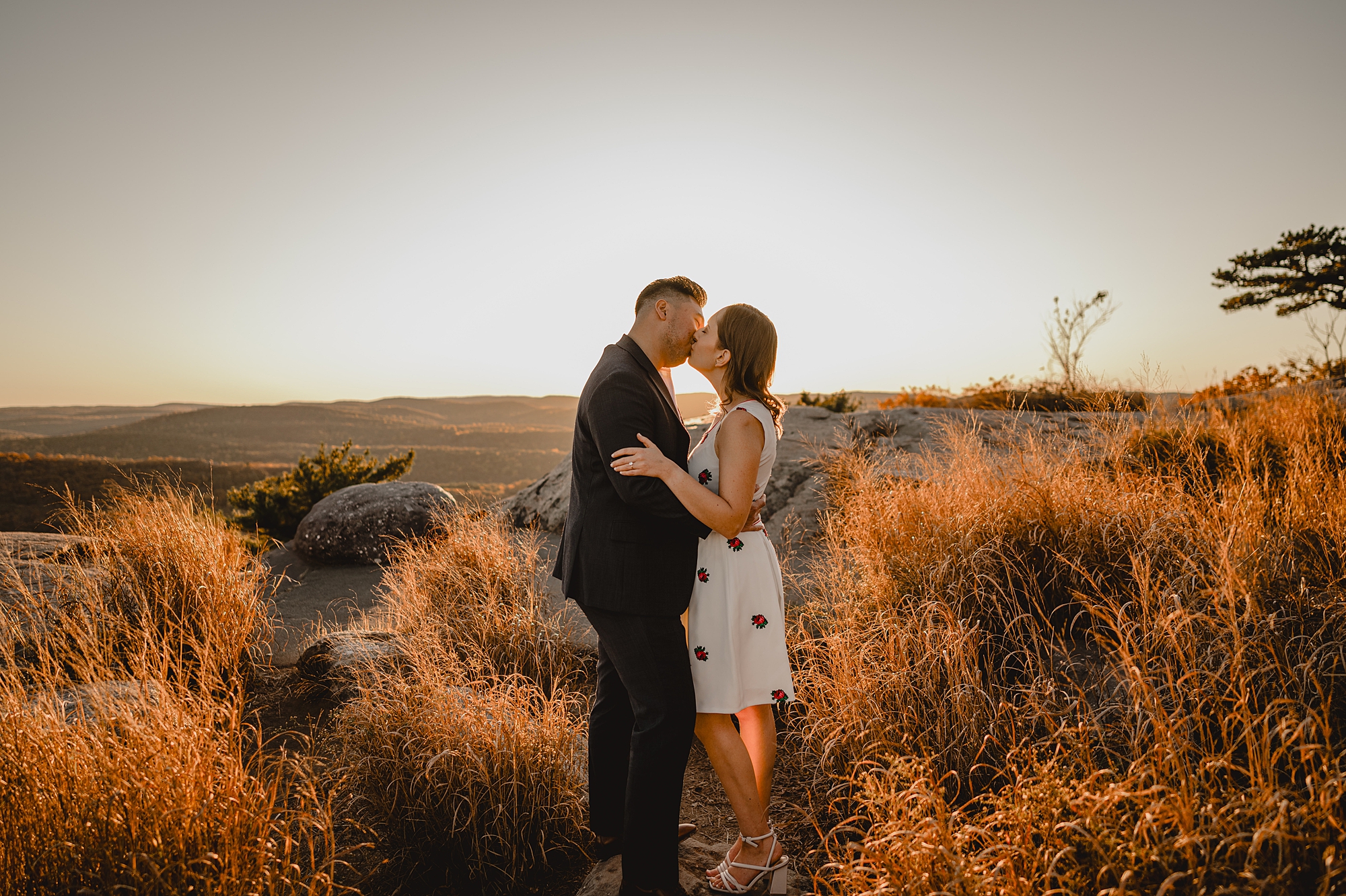man and woman kiss among orange foliage during fall engagement session on Bear Mountain