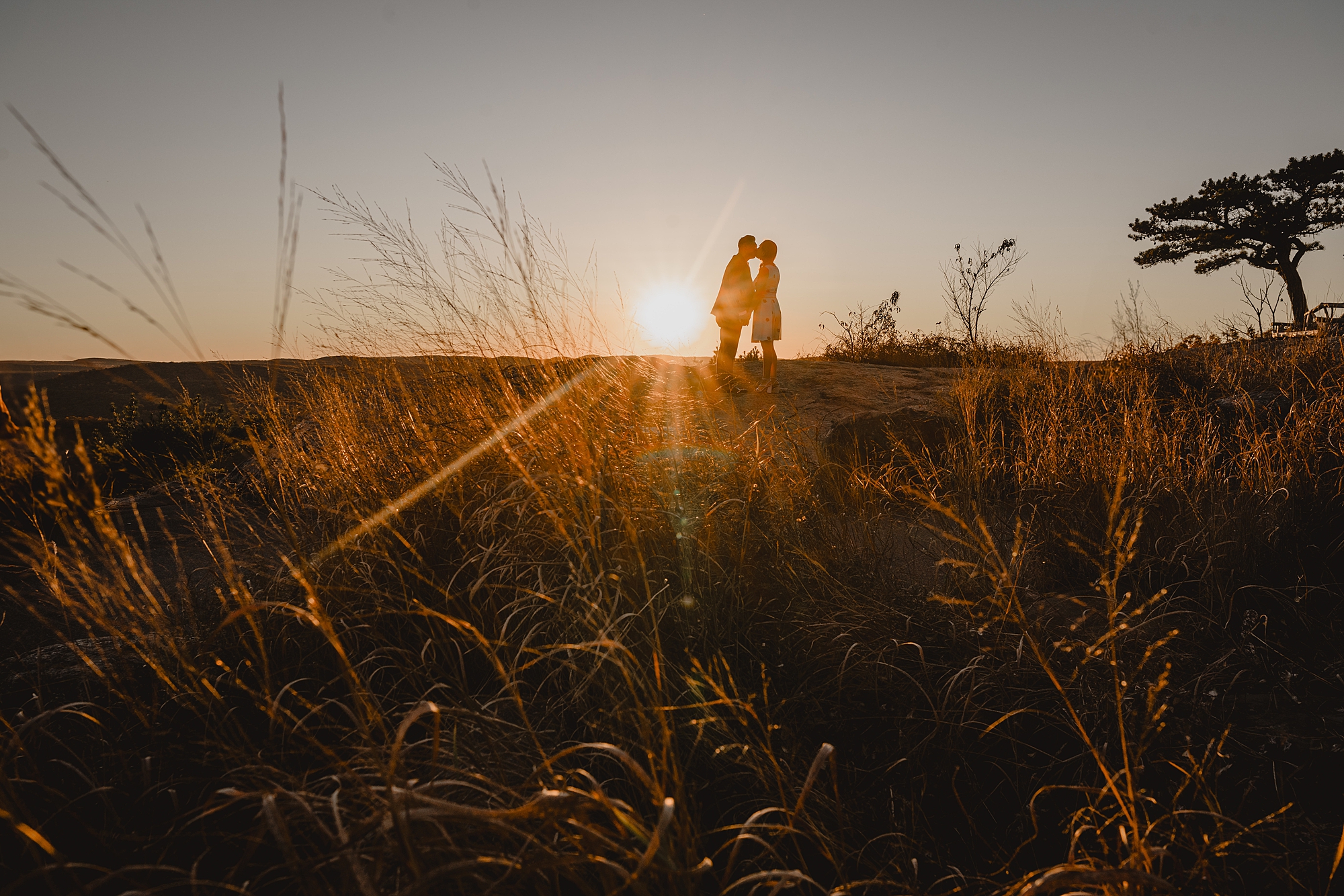 couple stands on top of mountain at sunset during fall engagement session on Bear Mountain