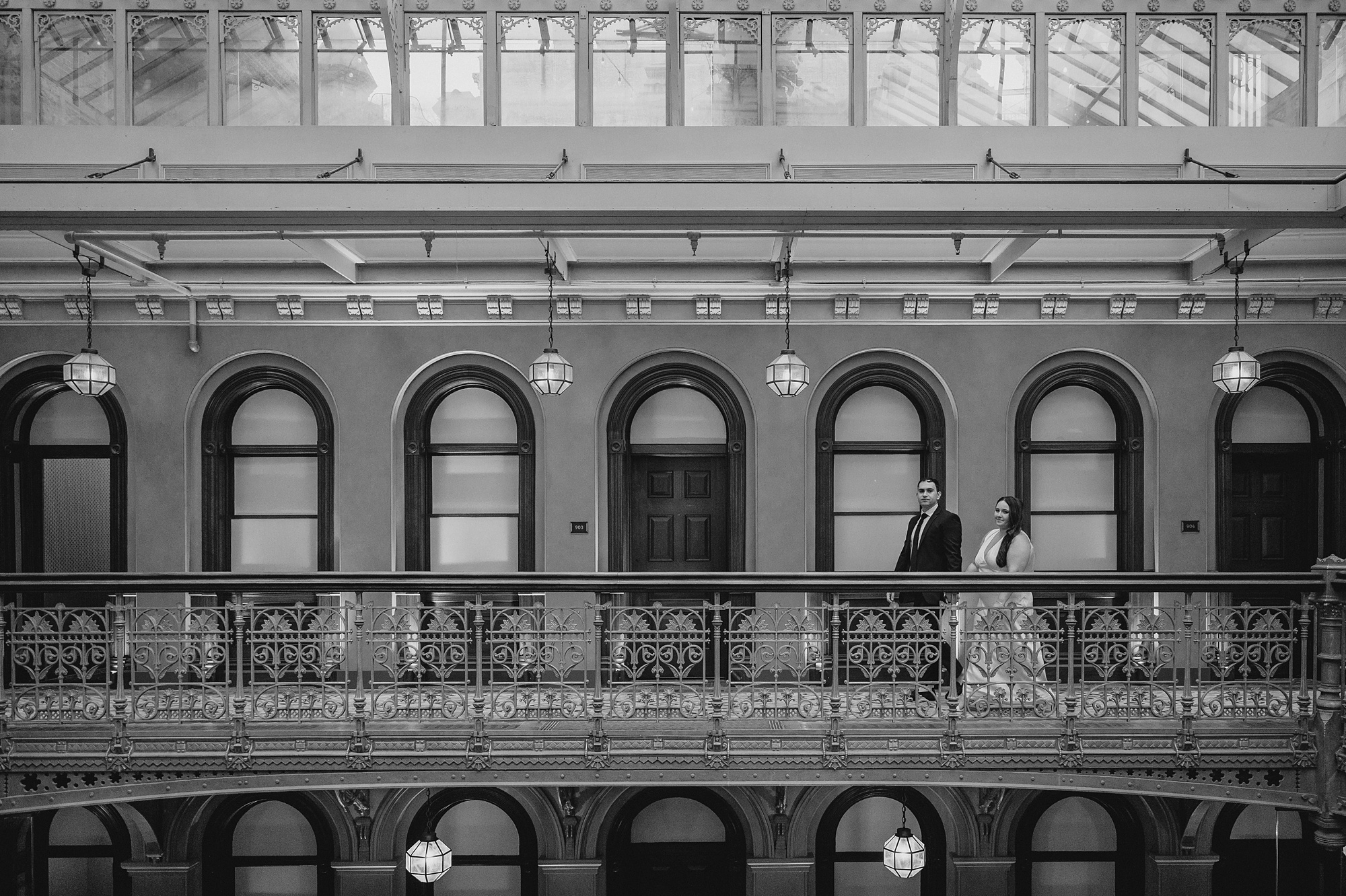 couple walks along balcony inside atrium during their Beekman Hotel engagement portraits