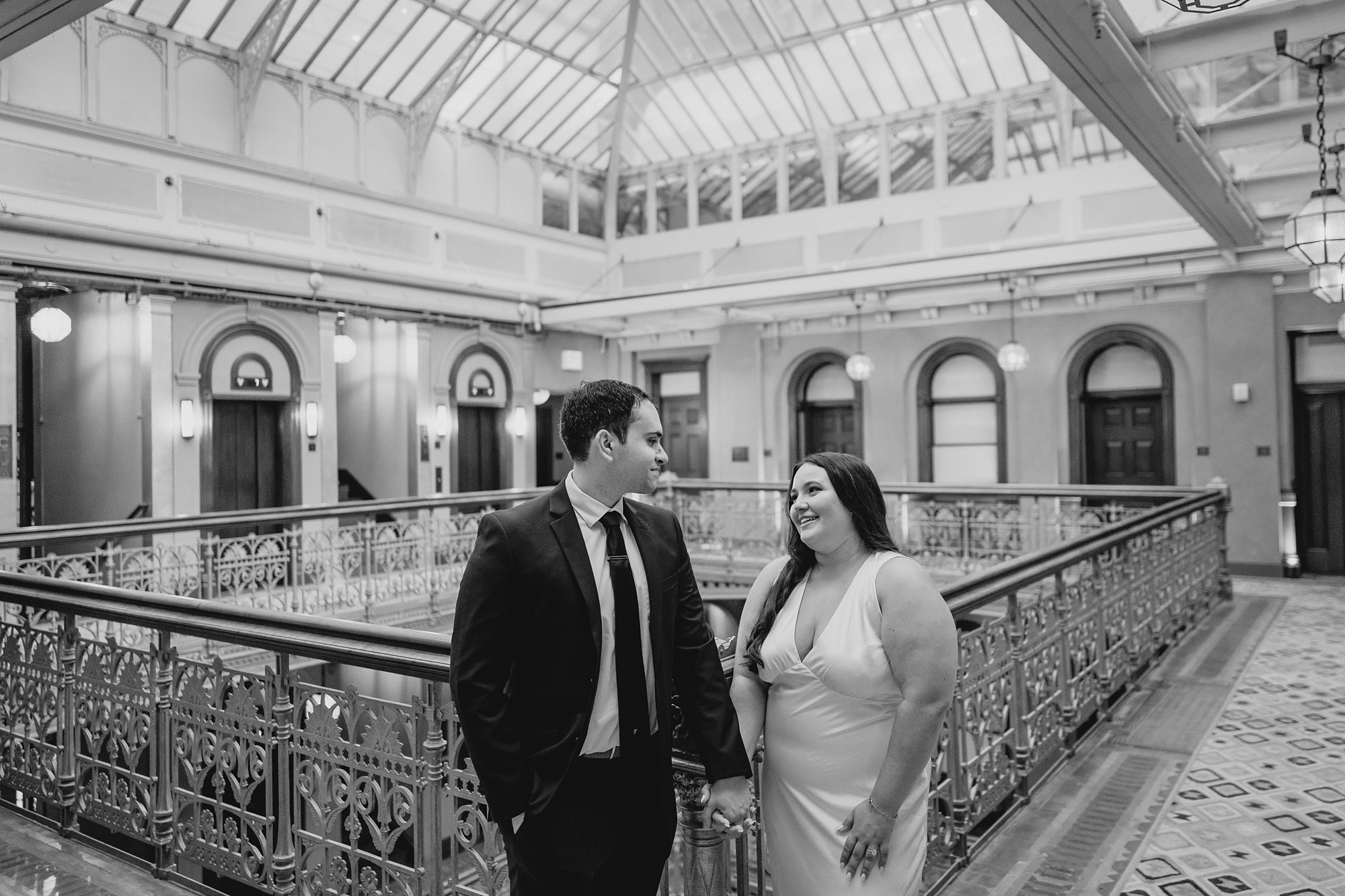 couple holds hands by wrought iron railing inside the Beekman Hotel
