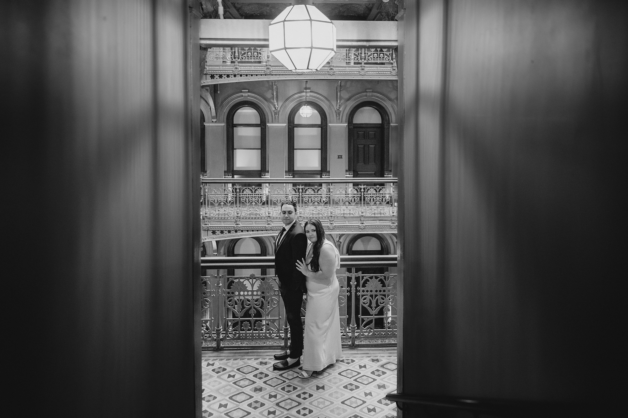 photo of couple standing in atrium of the Beekman Hotel through elevator doors