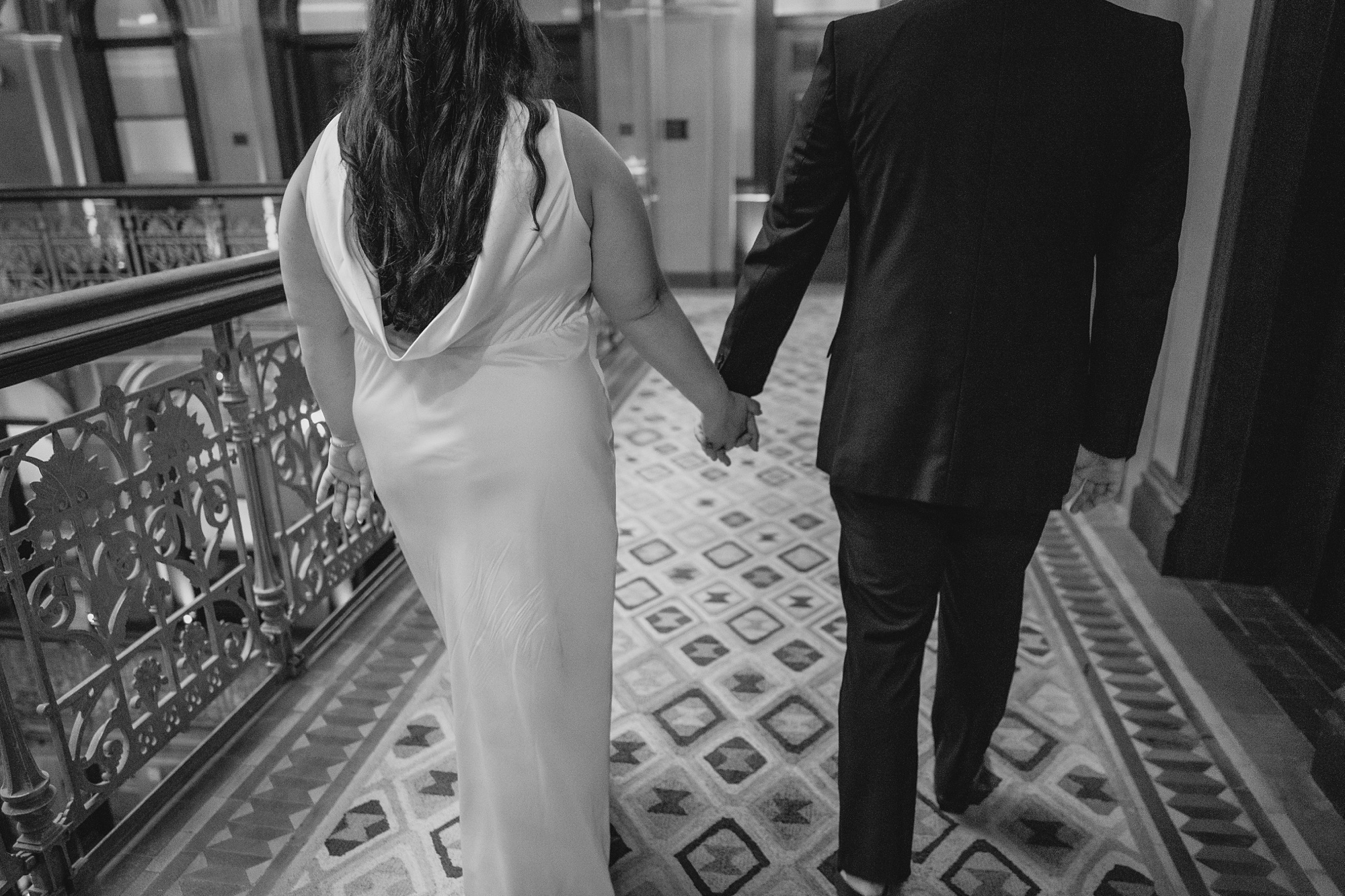 man and woman hold hands walking down hallway at the Beekman Hotel