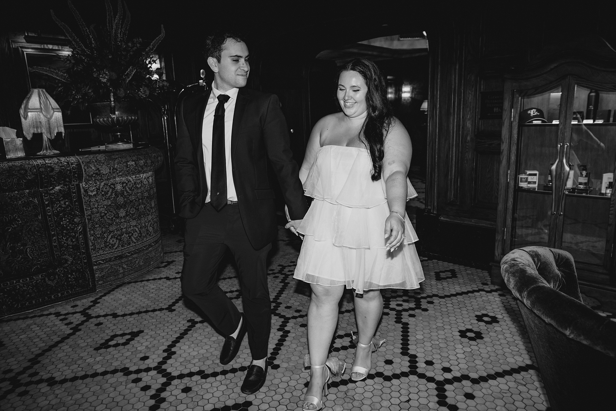 engaged couple holds hands walking through bar of the Beekman Hotel