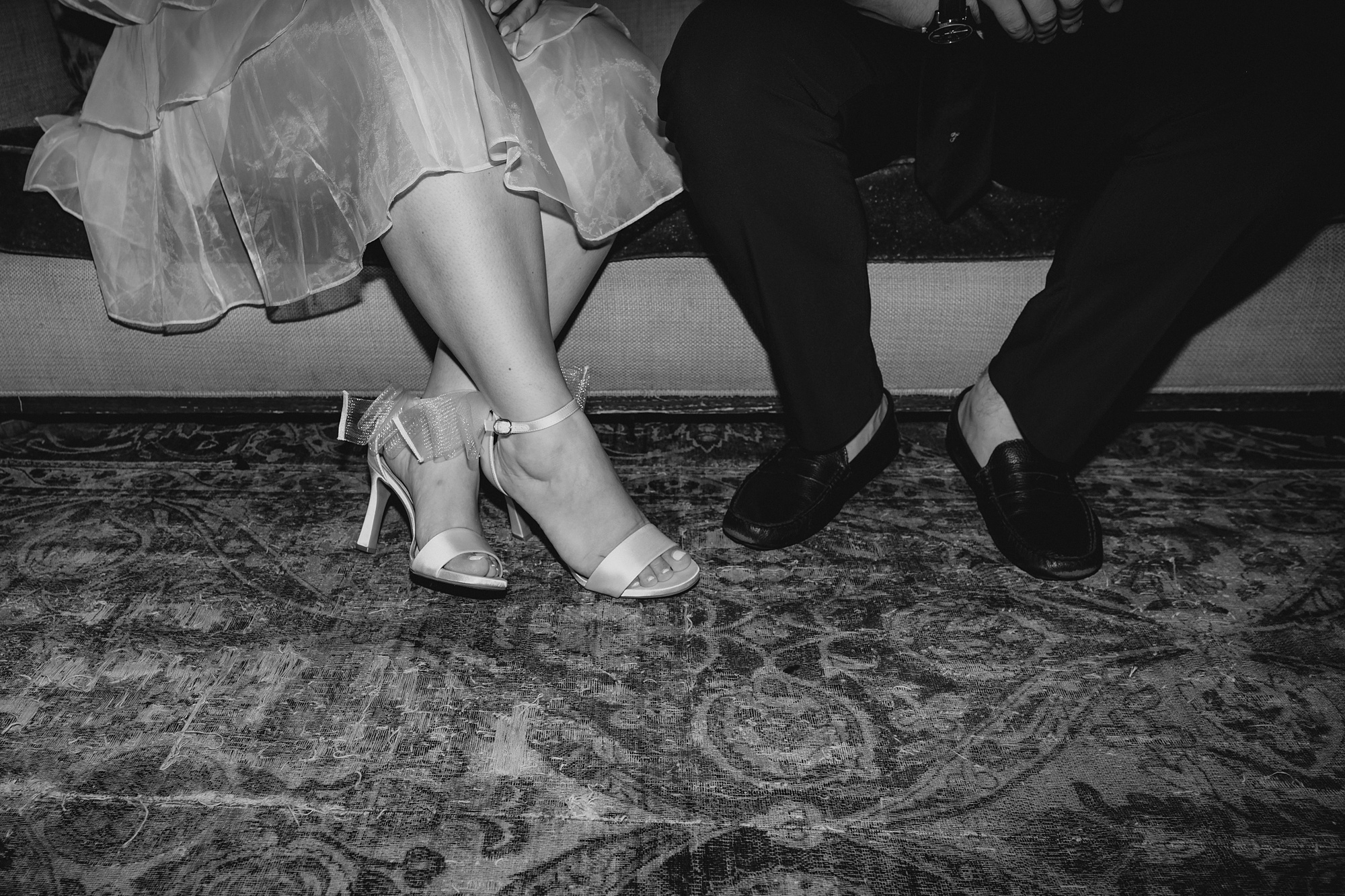 closeup of man and woman's shoes in front of sofa