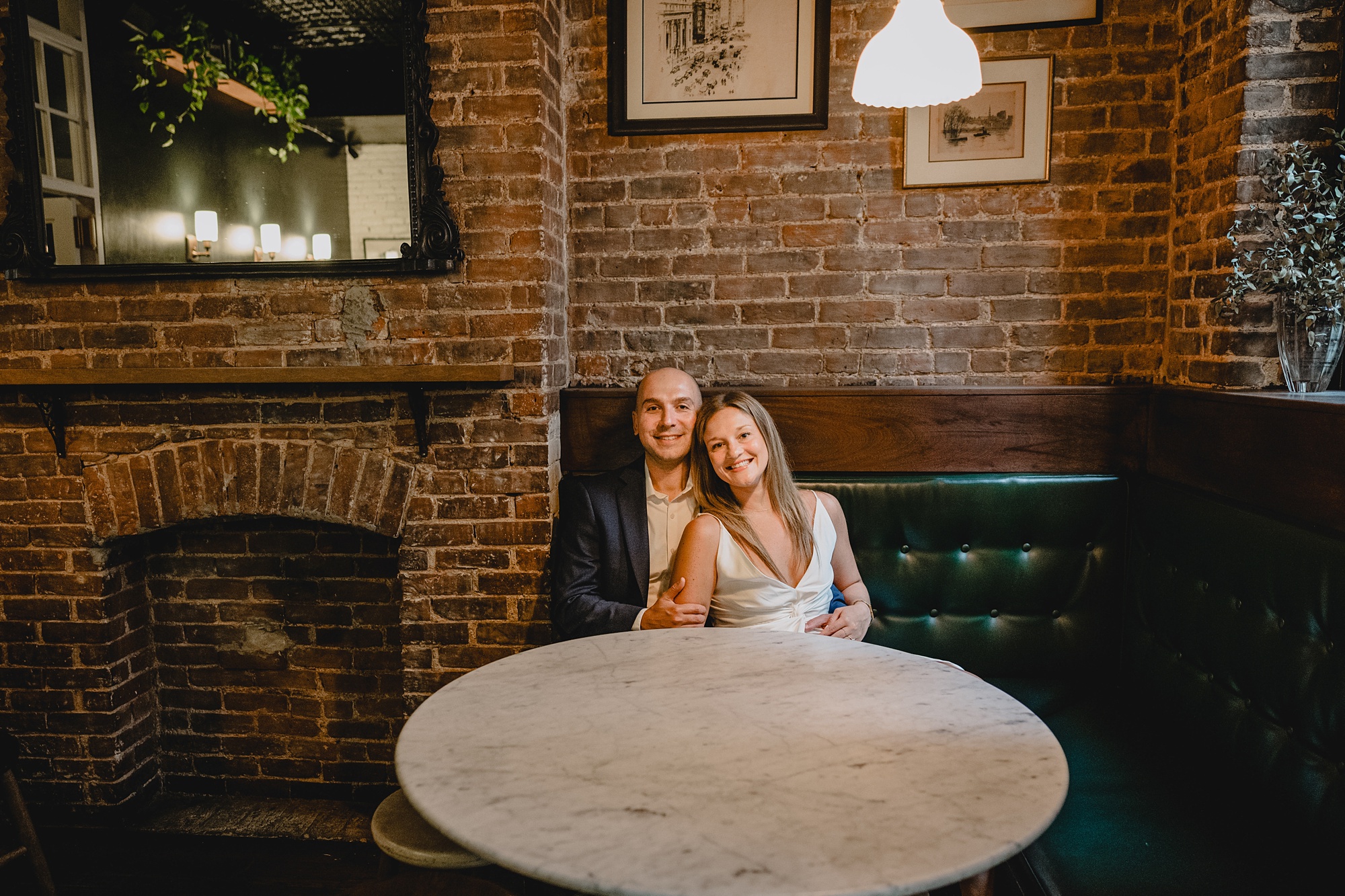 man and woman sit on leather sofa in NYC restaurant during Murray Hill engagement session