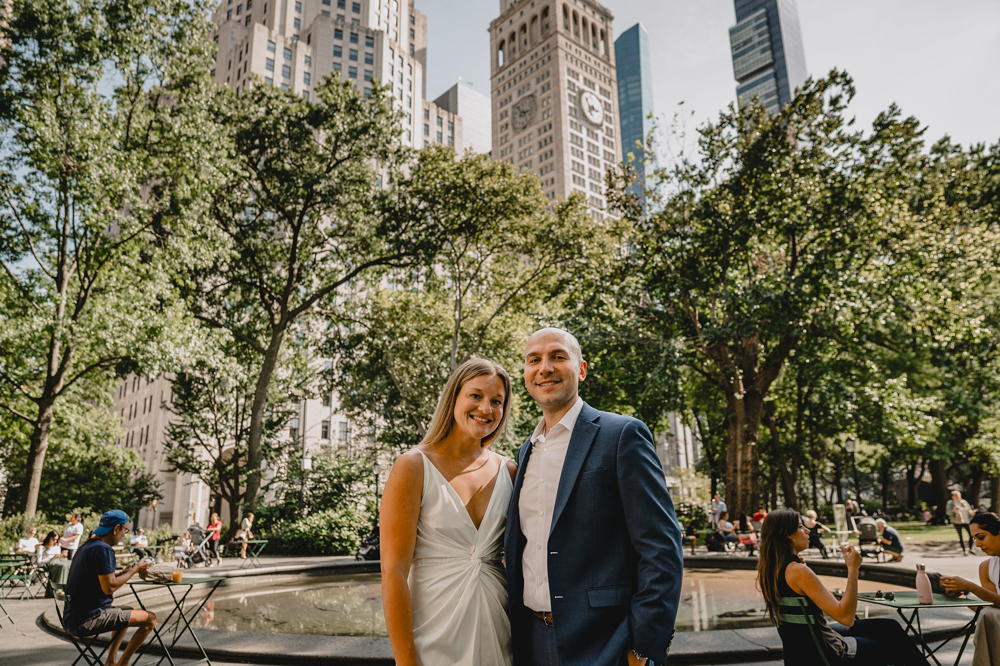 engaged couple stands in park in NYC in front of skyline and trees