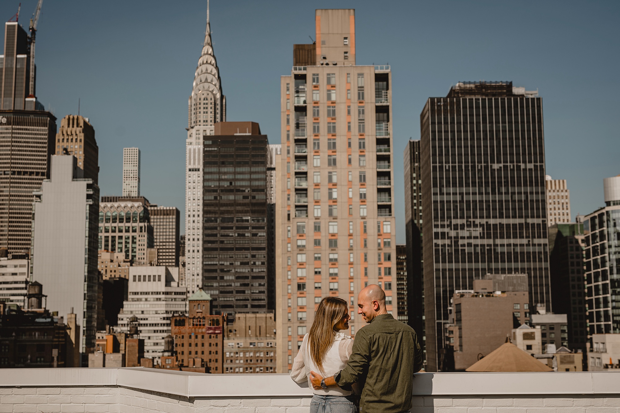 engaged couple stands on rooftop during Murray Hill engagement session