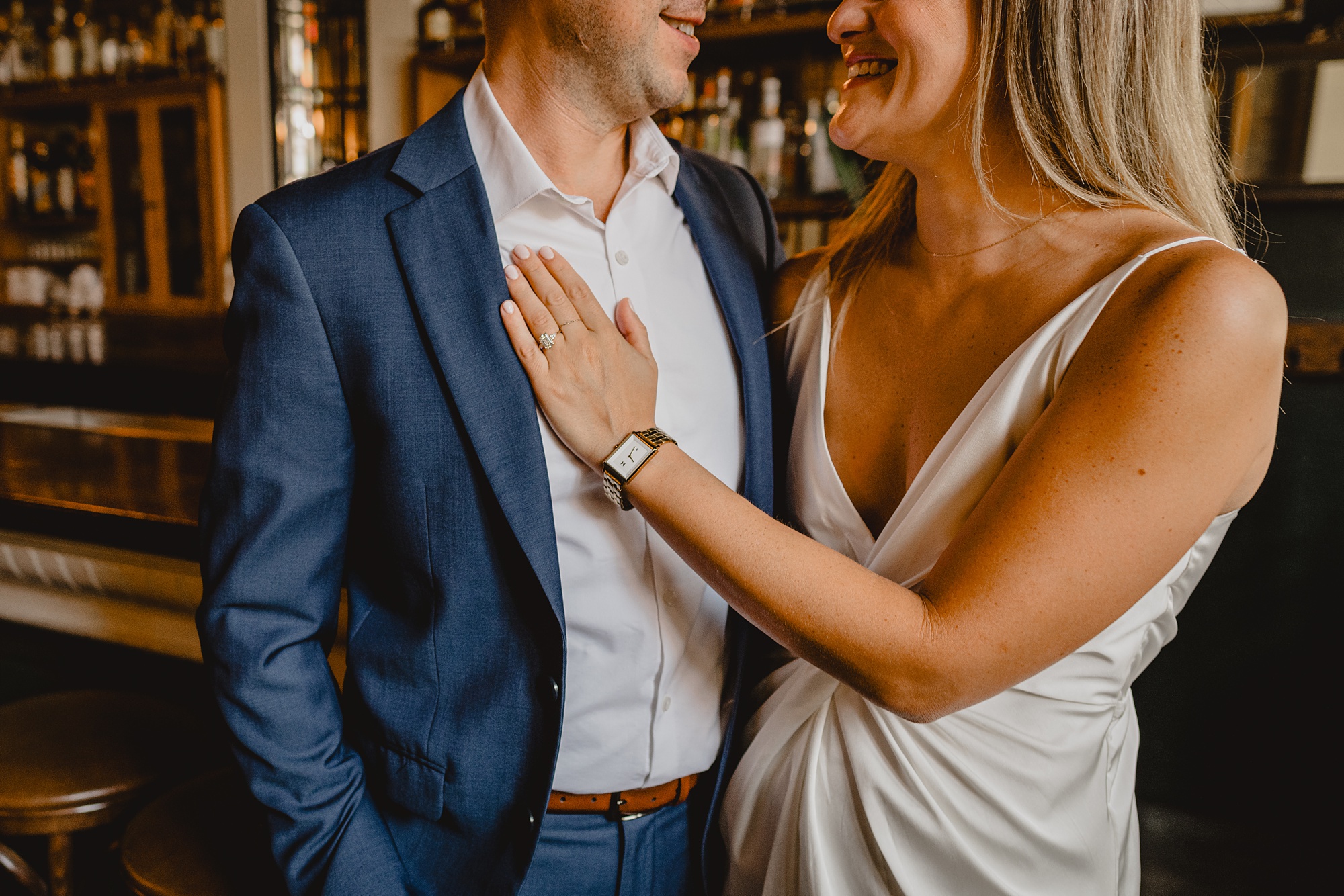 woman holds man's chest and suit jacket during Murray Hill engagement session