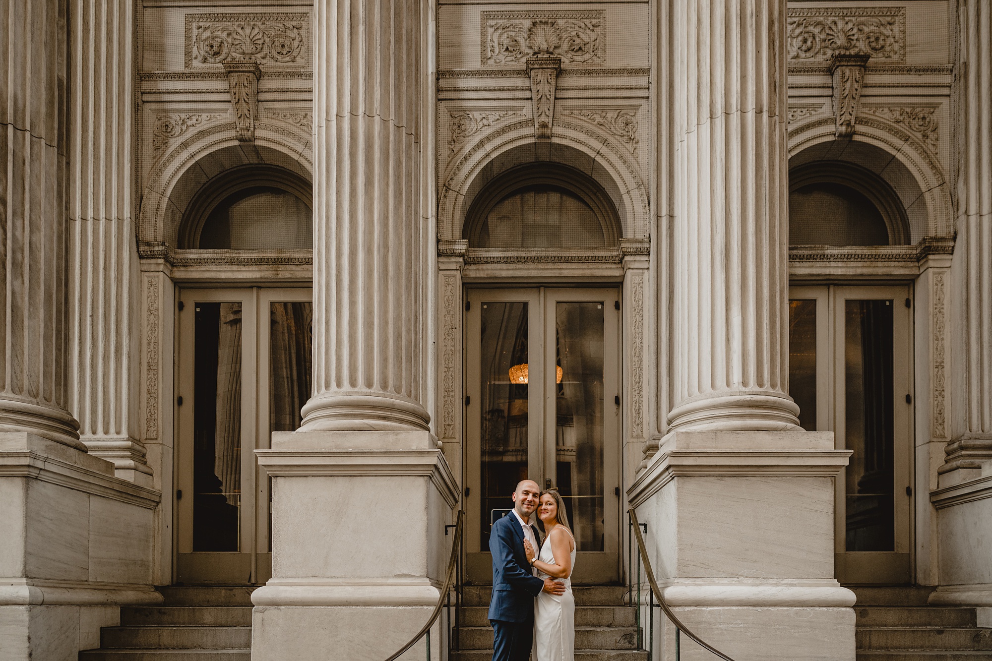 man and woman hug in between columns of building in NYC