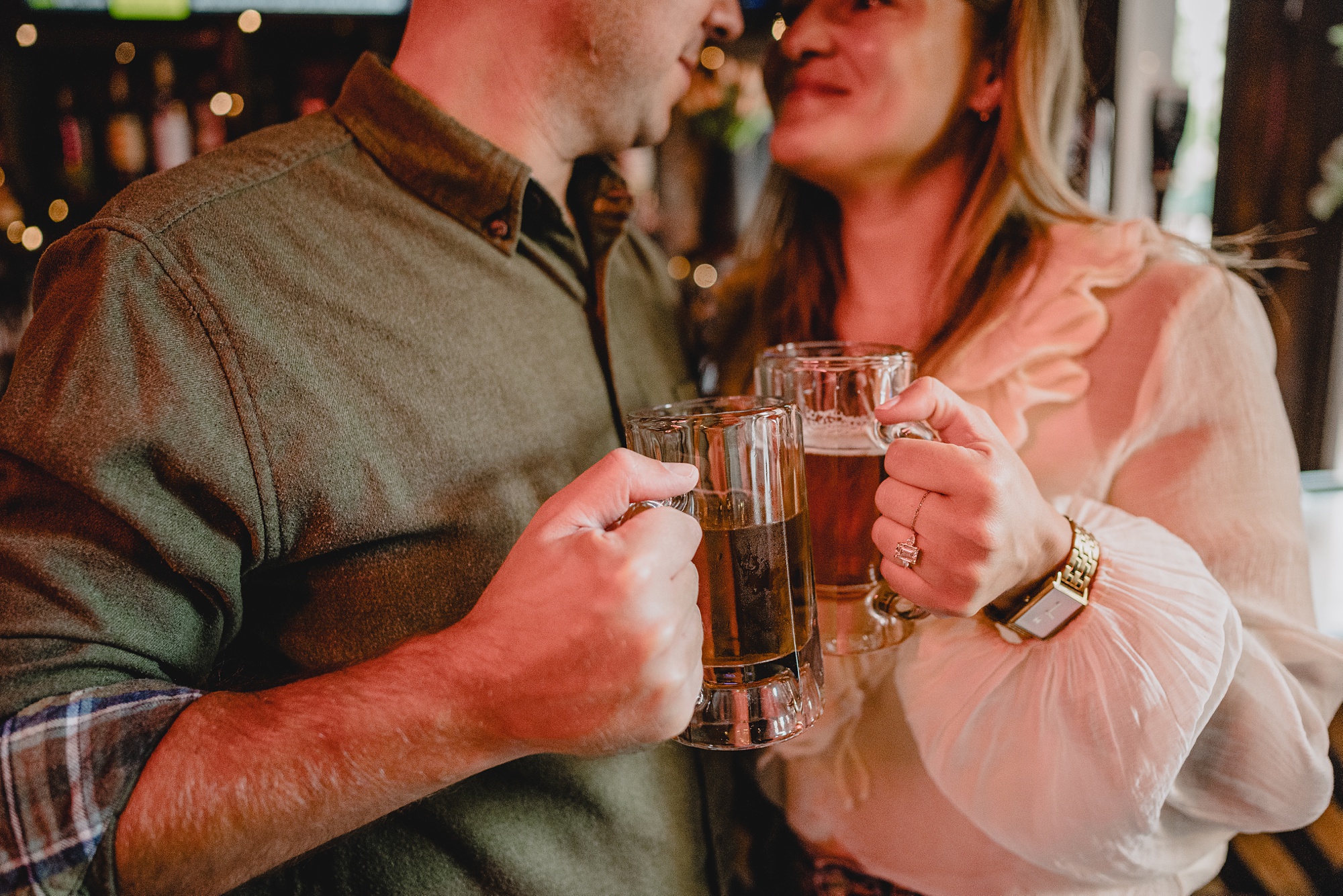 engaged couple holds up beers laughing during Murray Hill engagement session