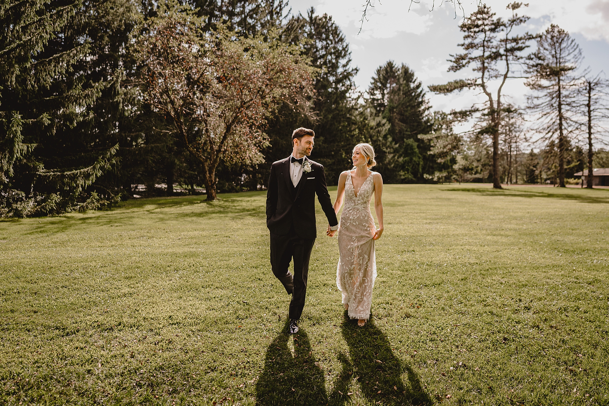 bride and groom hold hands walking on lawn at the Refinery at Perona Farms