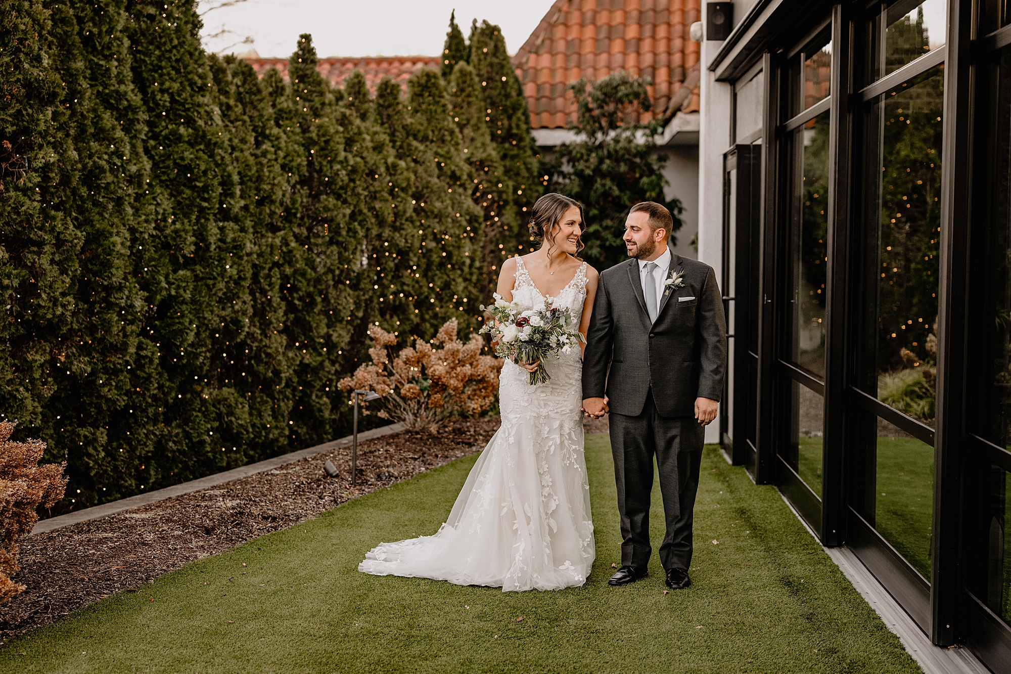 bride and groom walk by building at the Refinery at Perona Farms