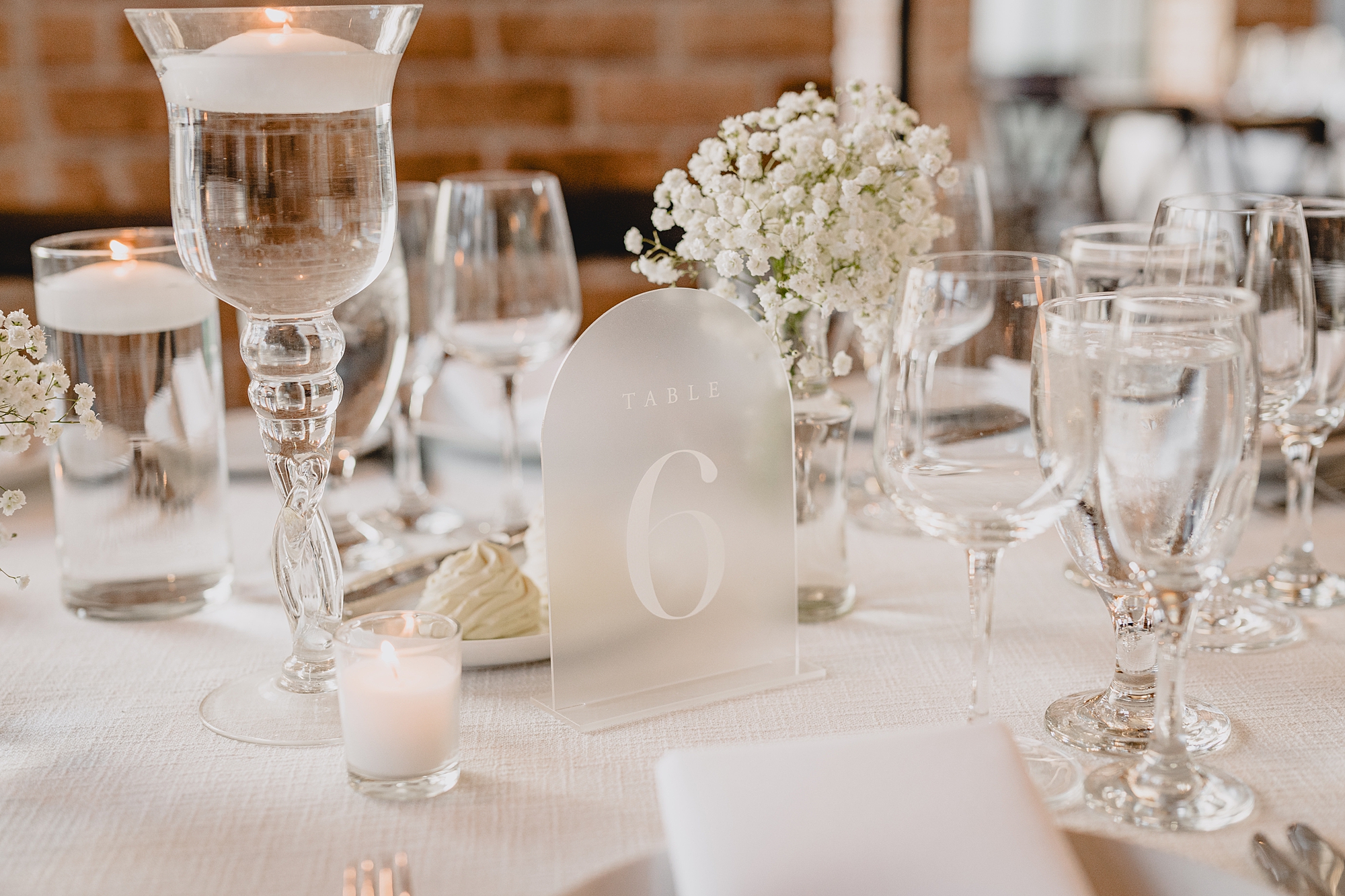 wedding reception place setting with glass and acrylic table numbers and baby's breath