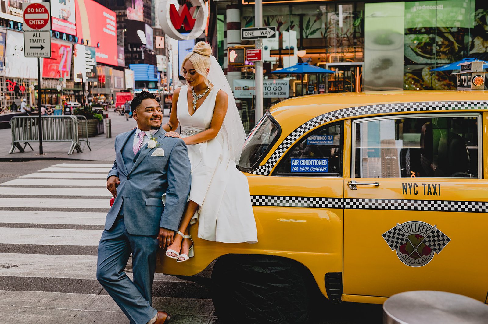 bride and groom pose with yellow NYC taxi cab in Times Square