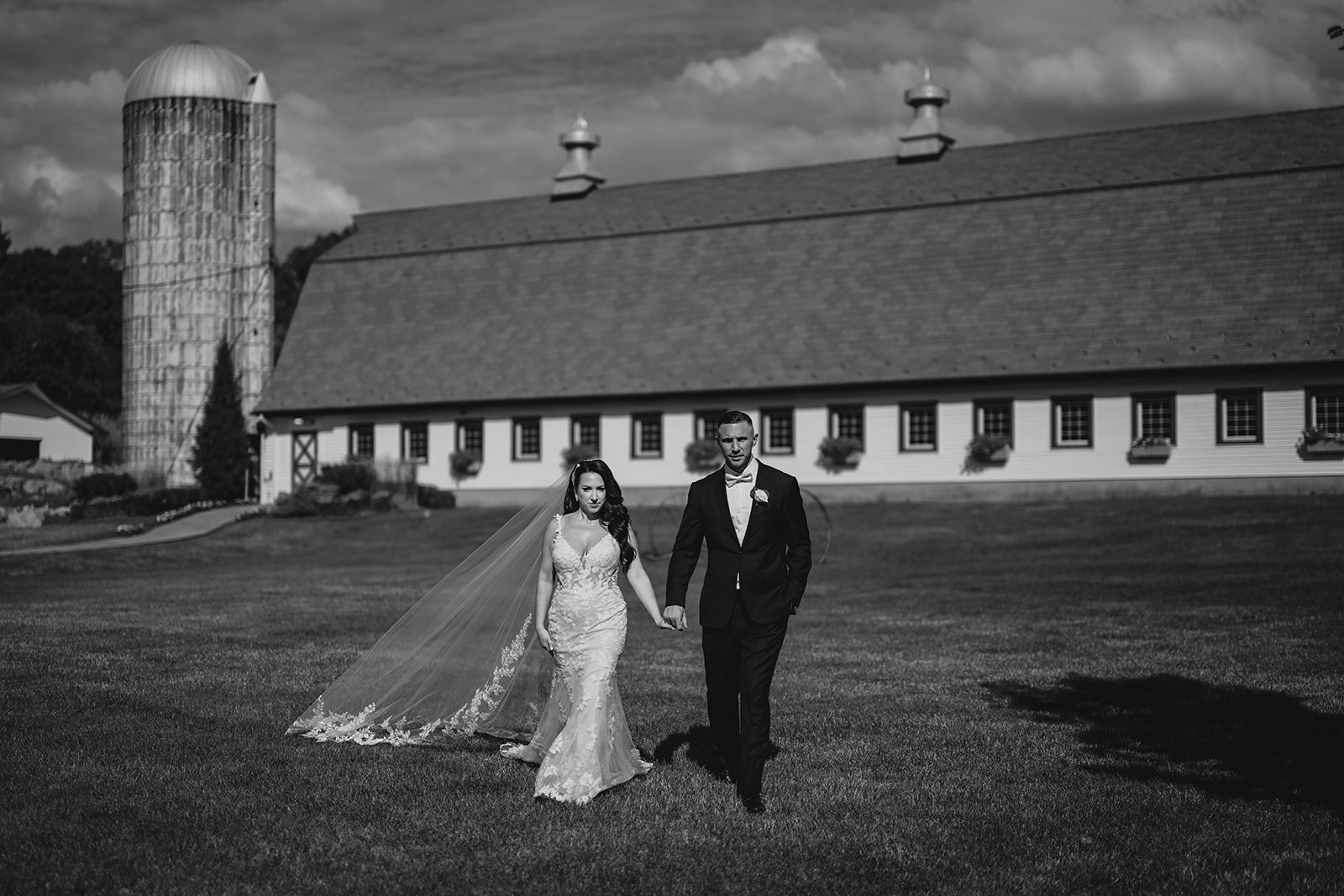 bride and groom hold hands in front of the Barn at Perona Farms