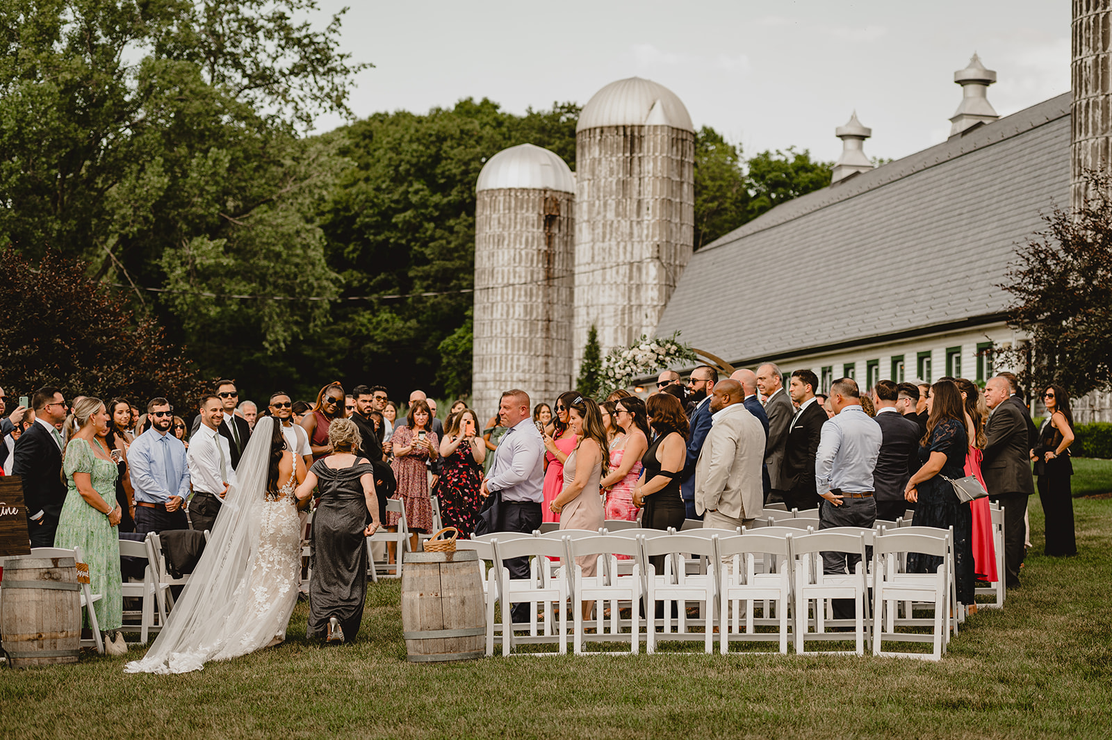 bride walks down aisle for ceremony on lawn at the Barn at Perona Farms