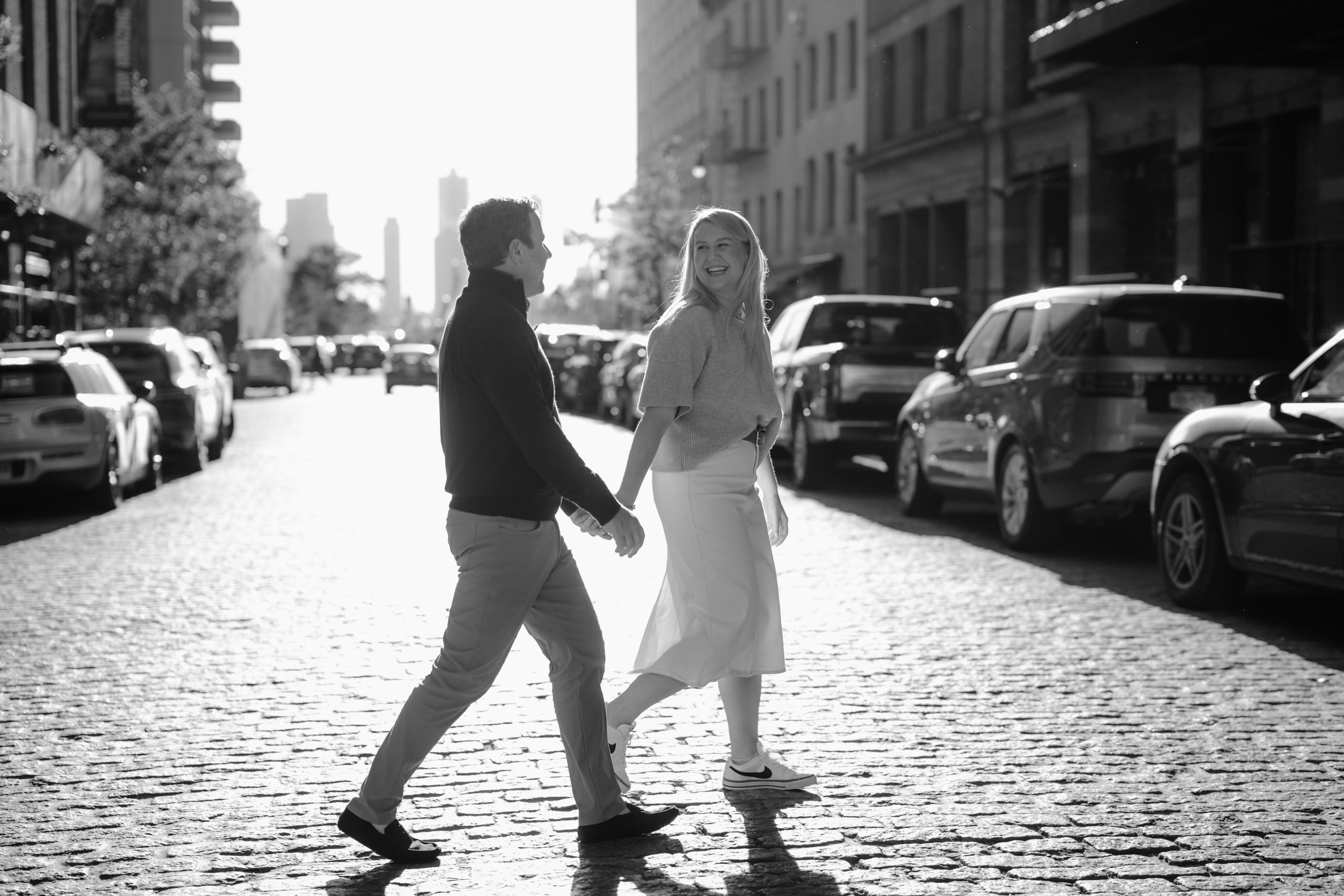 Couple walking hand-in-hand through the sunlit streets during their Tribeca NYC engagement session.