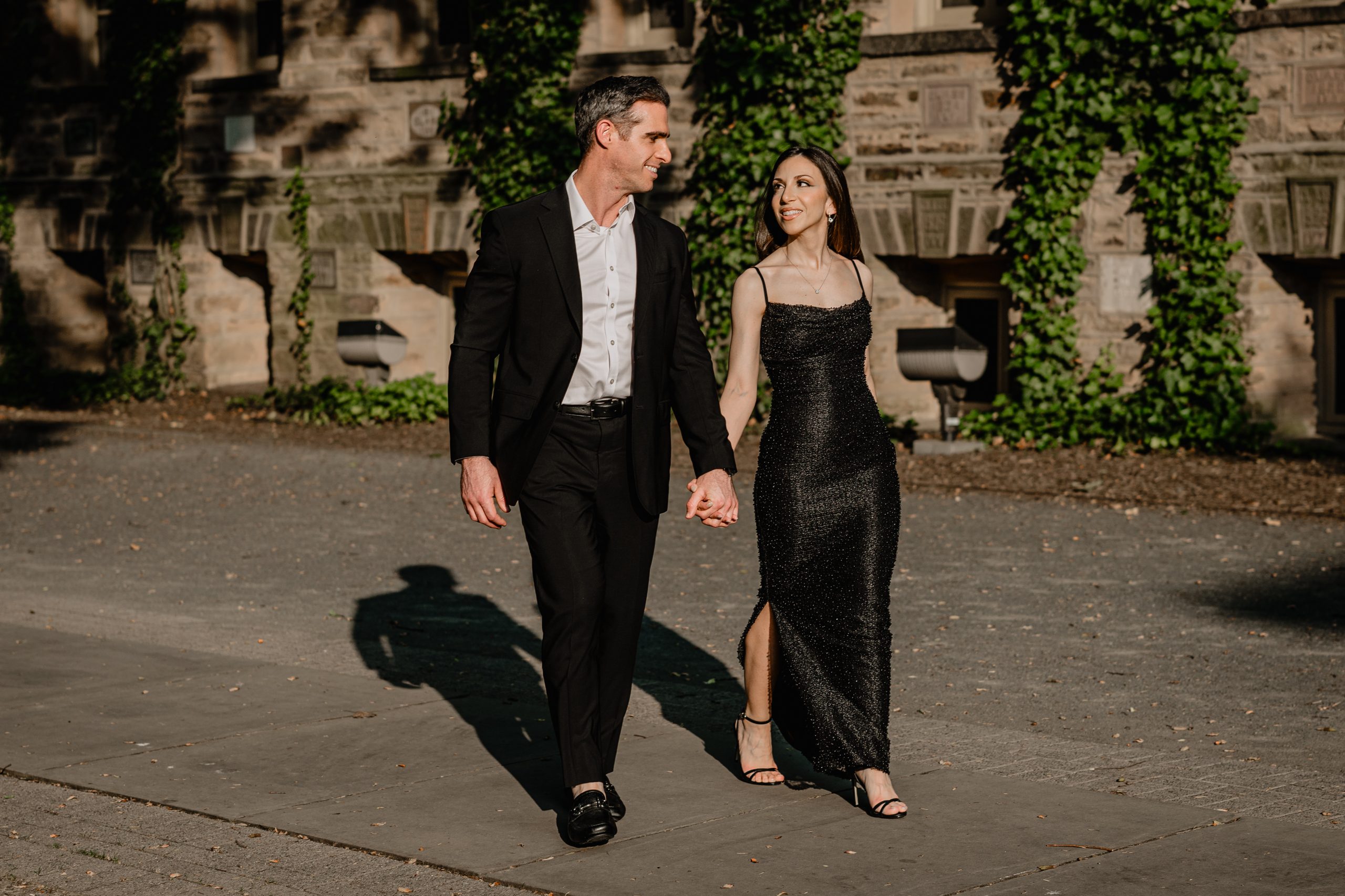 Couple walking hand in hand in golden evening light during their Princeton University engagement session.