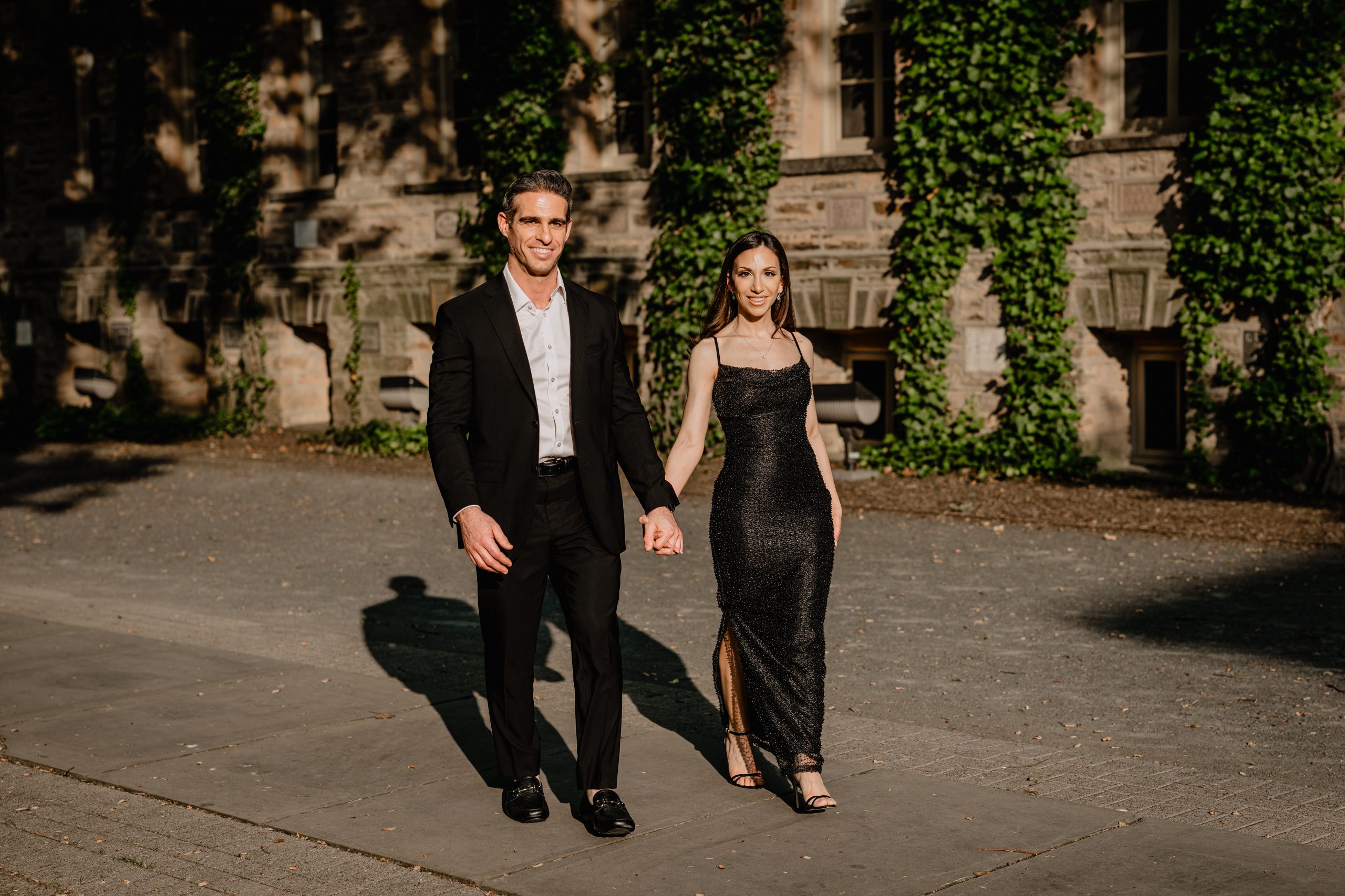 Couple walking hand in hand in golden evening light during their Princeton University engagement session.