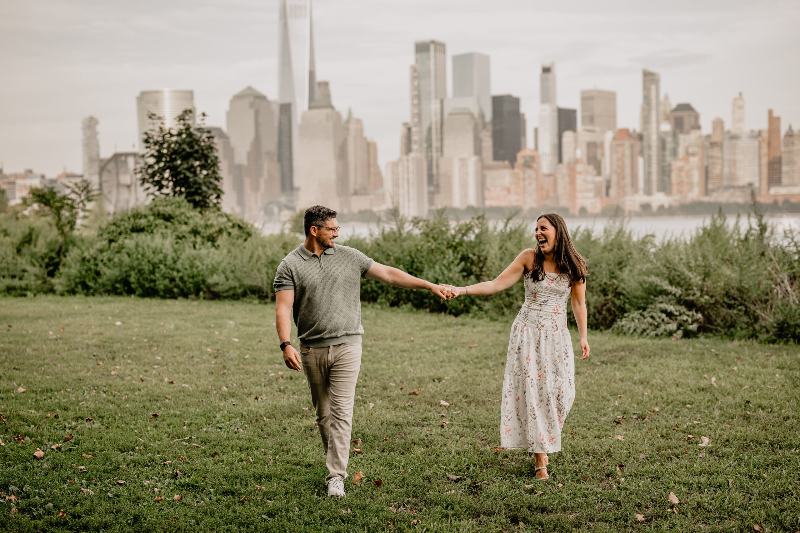 Couple walking hand-in-hand and laughing during their Jersey City Engagement at Paulus Hook.