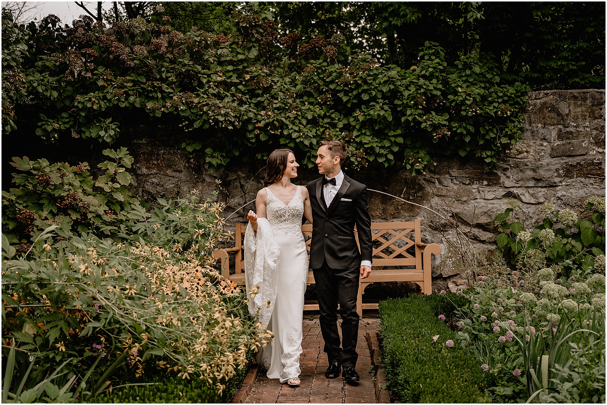 Couple walking through the garden during their Summer Crossed Keys Estate wedding.