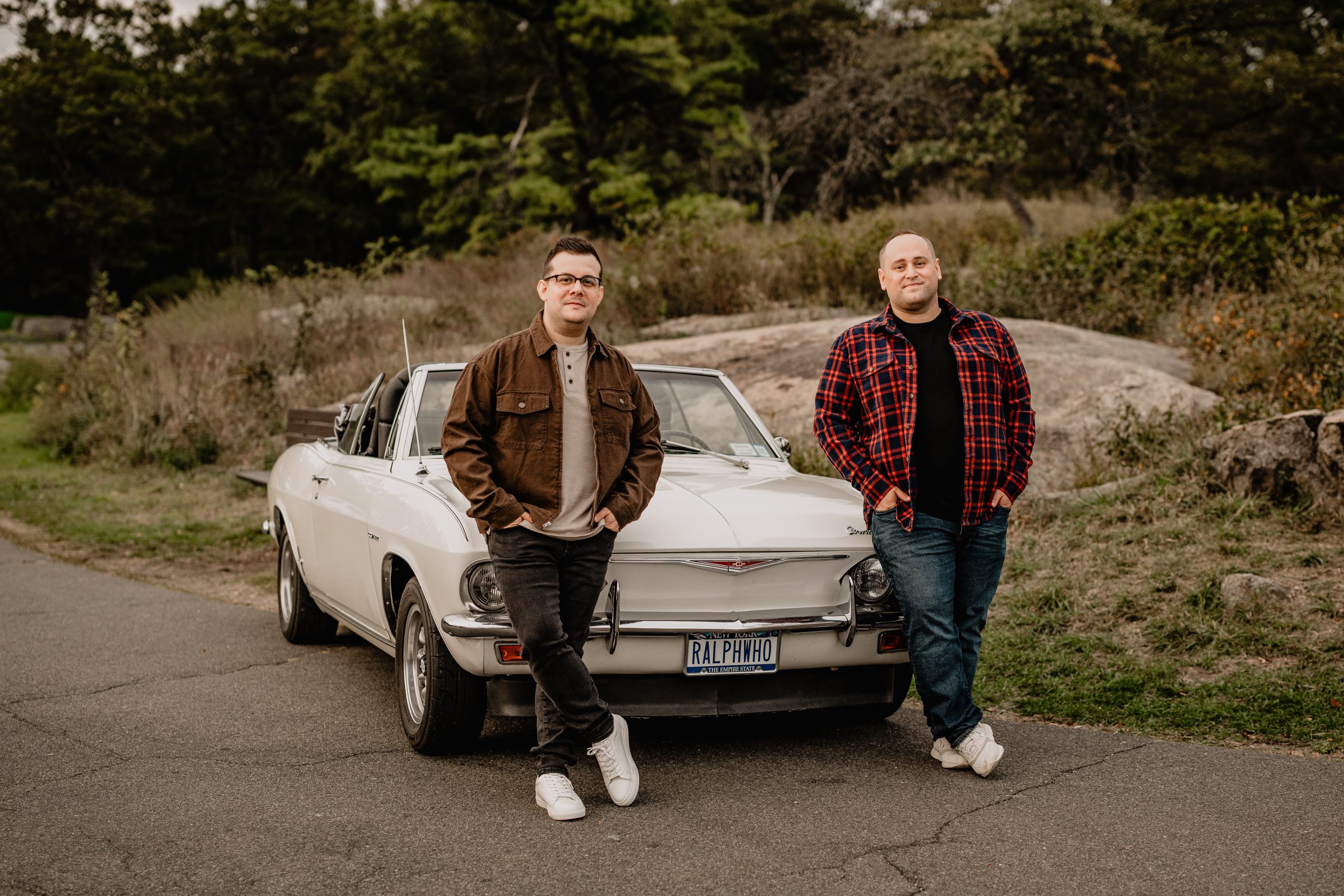 Trevor and Josh posing beside a classic family car during their Bear Mountain engagement session.