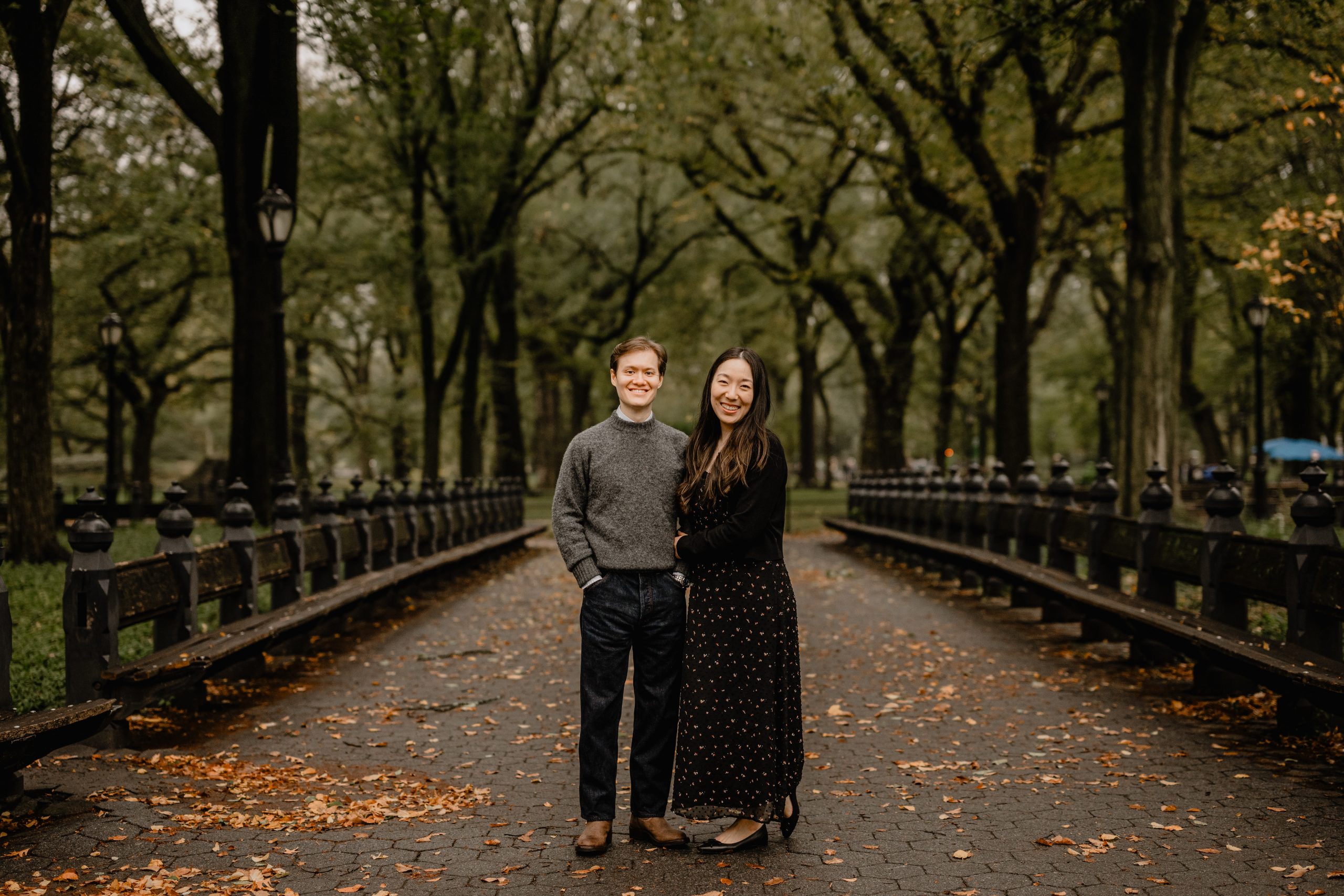 Kimberly and Peter walking through the tree-lined paths of Central Park during their fall engagement session at Central Park.
