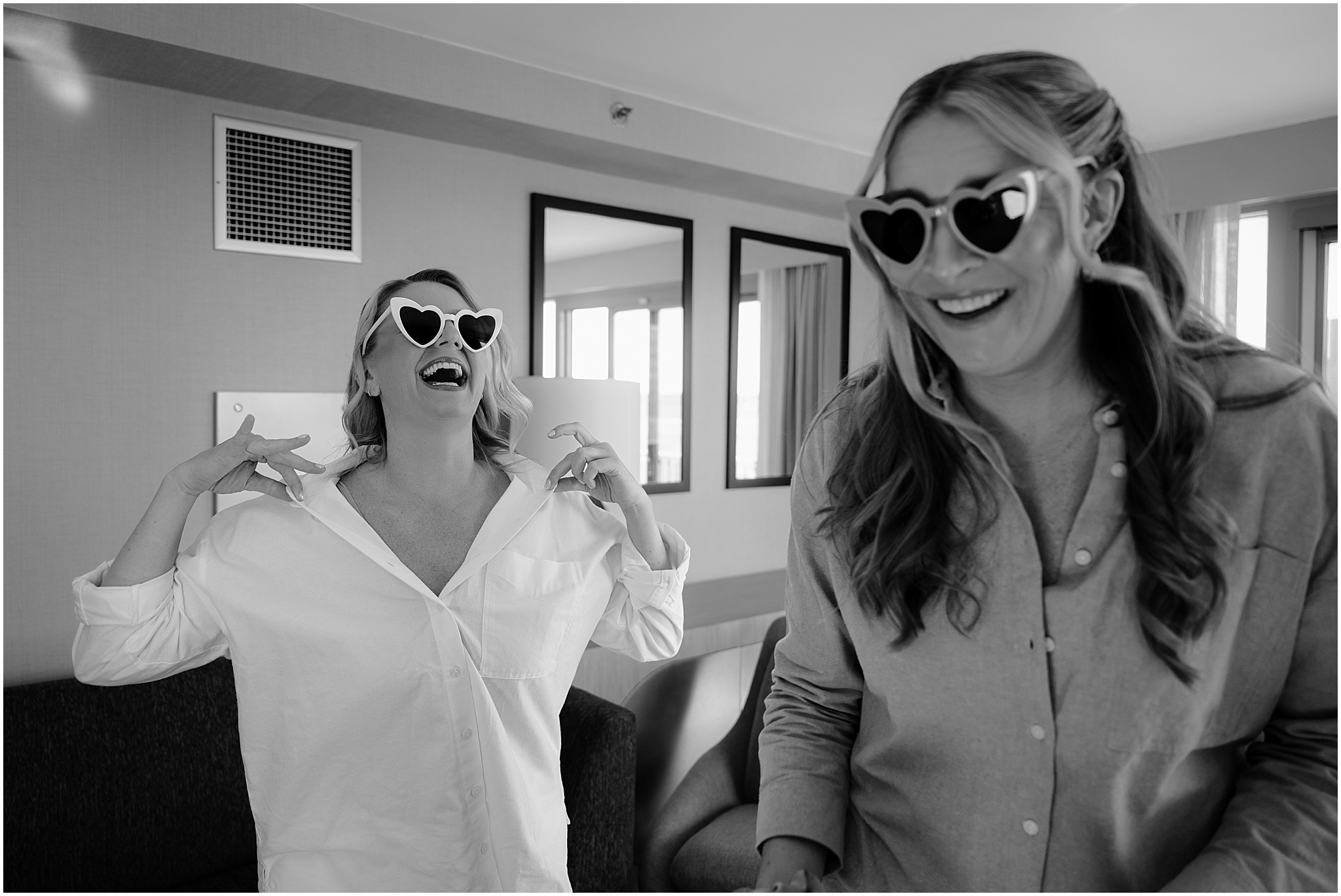 Bride laughing with one of her bridesmaids wearing heart-shaped sunglasses before their Colorful Fall Wedding at Liberty House.