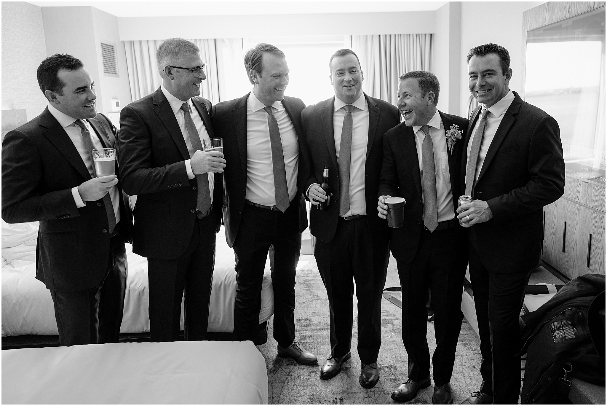 Groom laughing and enjoying a drink with his groomsmen before the ceremony at their Colorful Fall Wedding at Liberty House.
