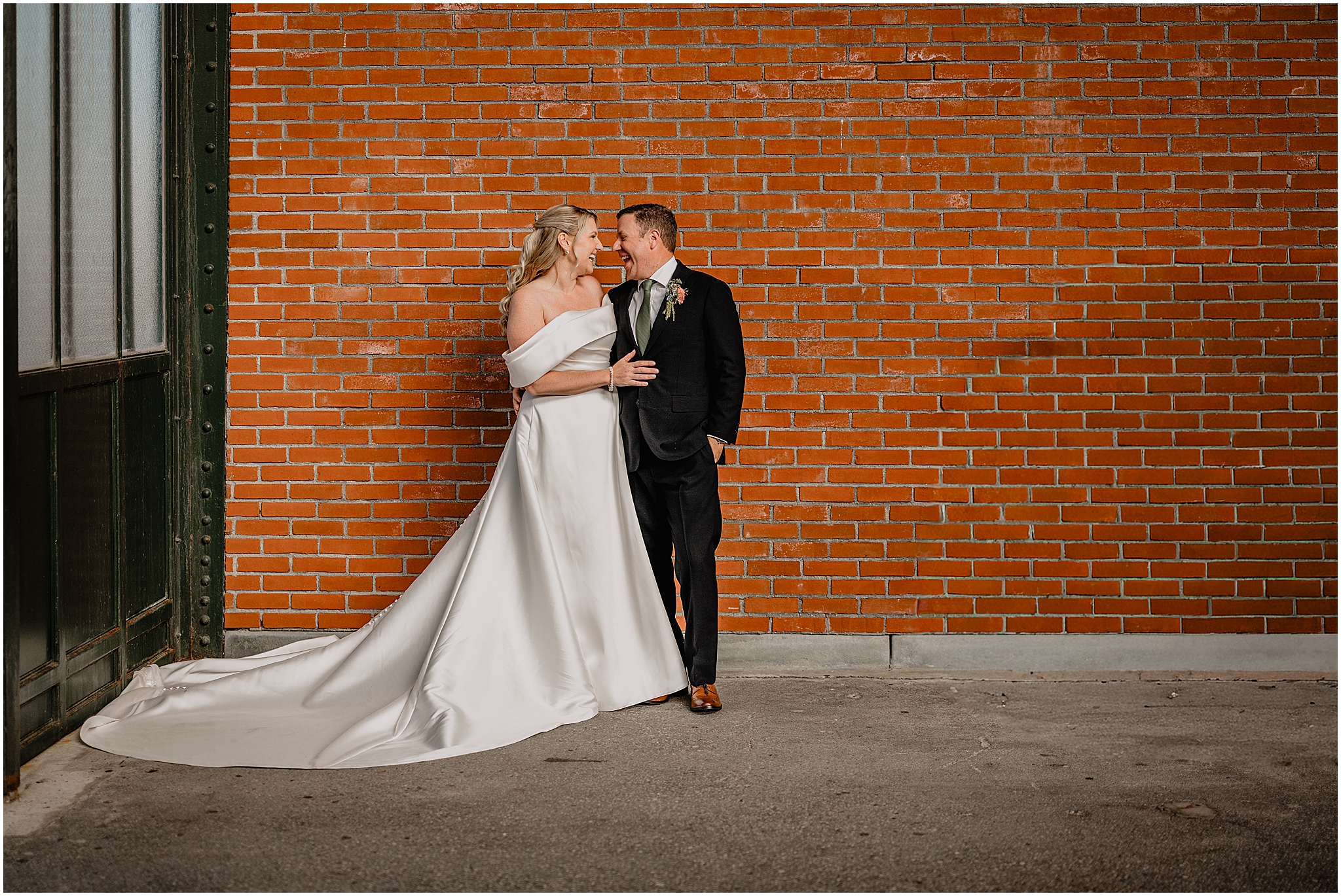 Couple’s portraits smiling at each other with a brick wall backdrop at their Colorful Fall Wedding at Liberty House.