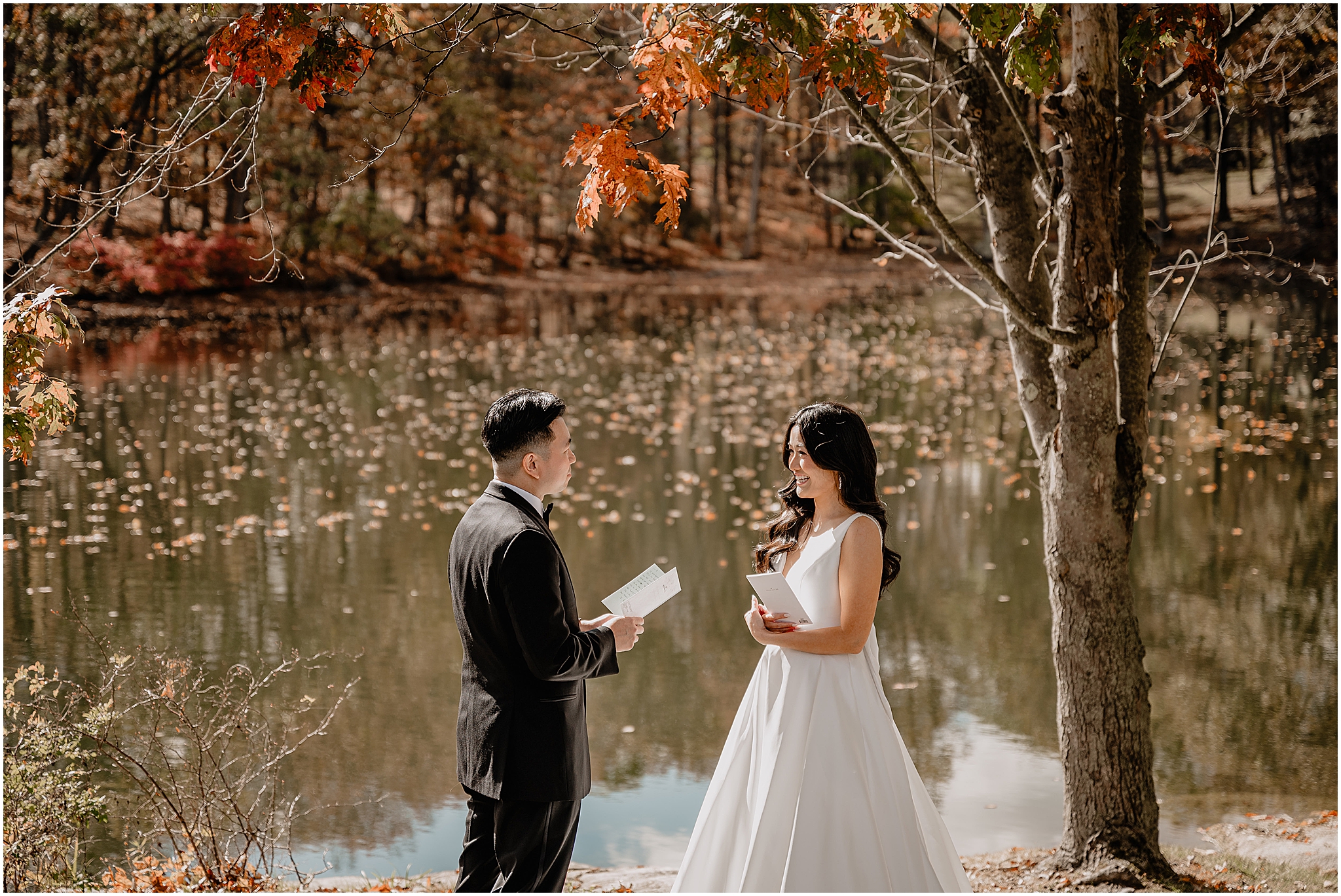 Couple reading each other's vows by the lake during their fall wedding at Perona Farms Reserve, exchanging heartfelt words surrounded by autumn beauty before their wedding.