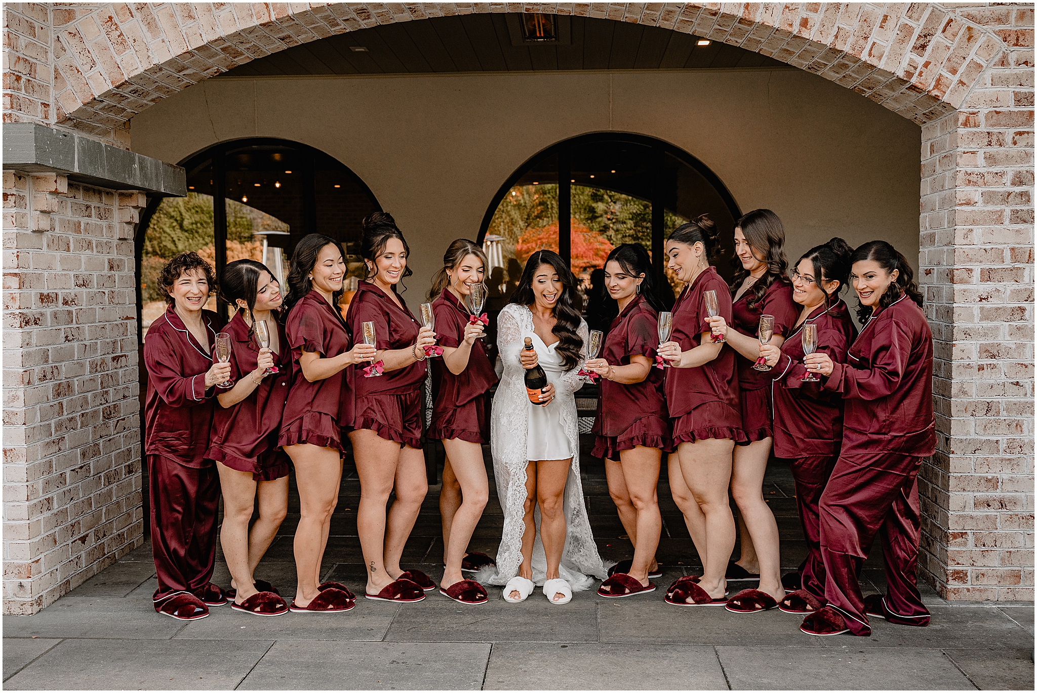 Bride opening a bottle of champagne with her bridesmaids before her fall wedding at Perona Farms Refinery, celebrating together before the ceremony.