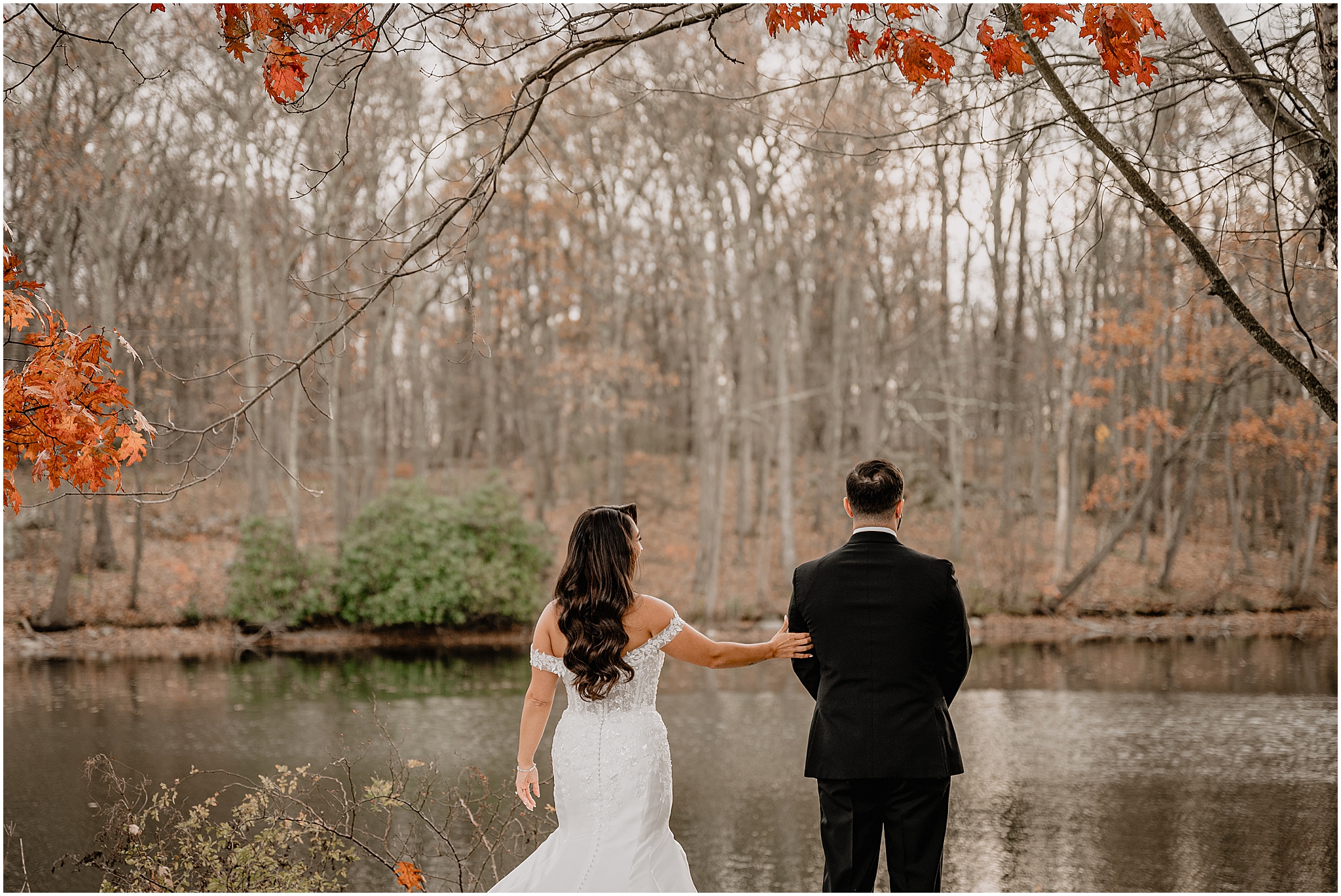 Couple’s first look by the lake during a fall wedding at Perona Farms Refinery, sharing an intimate and emotional moment together.