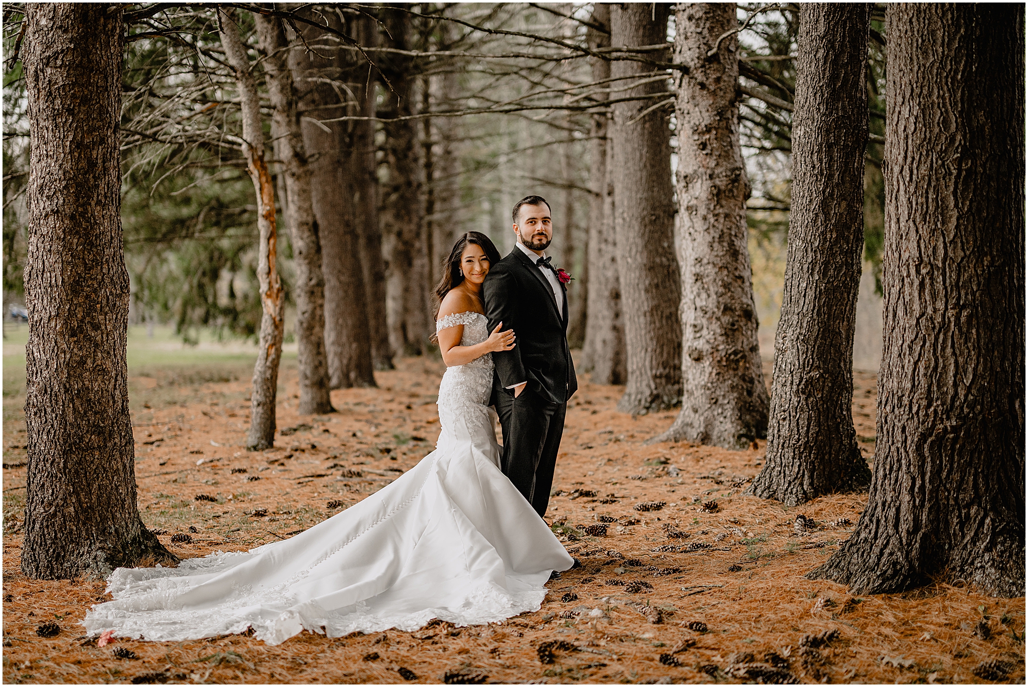 Couple’s stunning portraits by the trees before their fall wedding at Perona Farms Refinery, surrounded by soft light and vibrant autumn foliage.