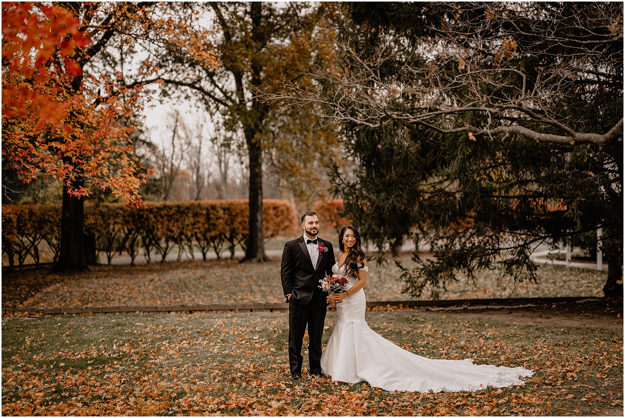 Couple’s stunning portraits in front of a beautiful autumn tree before their fall wedding at Perona Farms Refinery, bathed in soft light and surrounded by vibrant fall foliage.