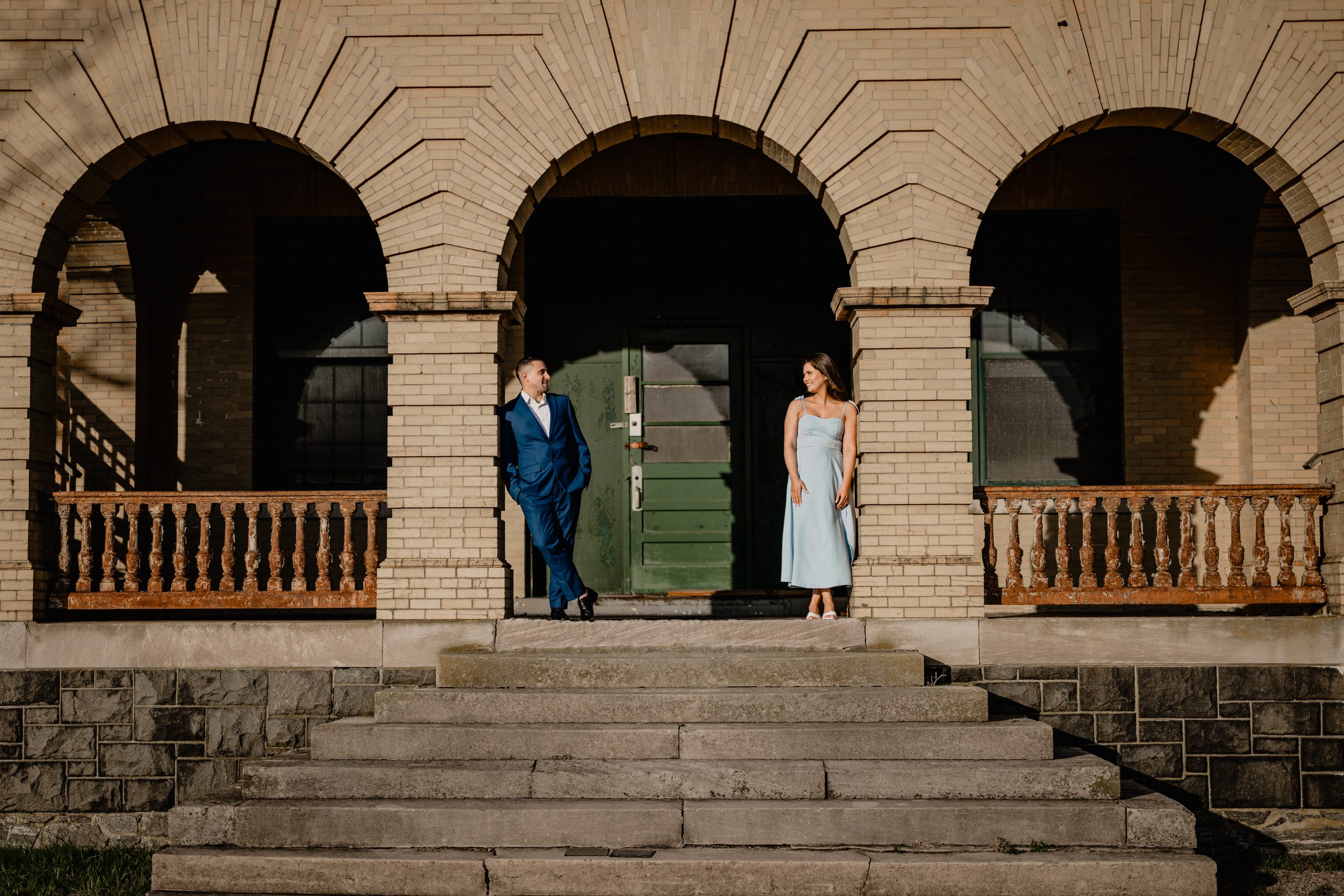 Couple at the top of the stairs by a brick archway on their engagement session at Sandy Hook Beach.